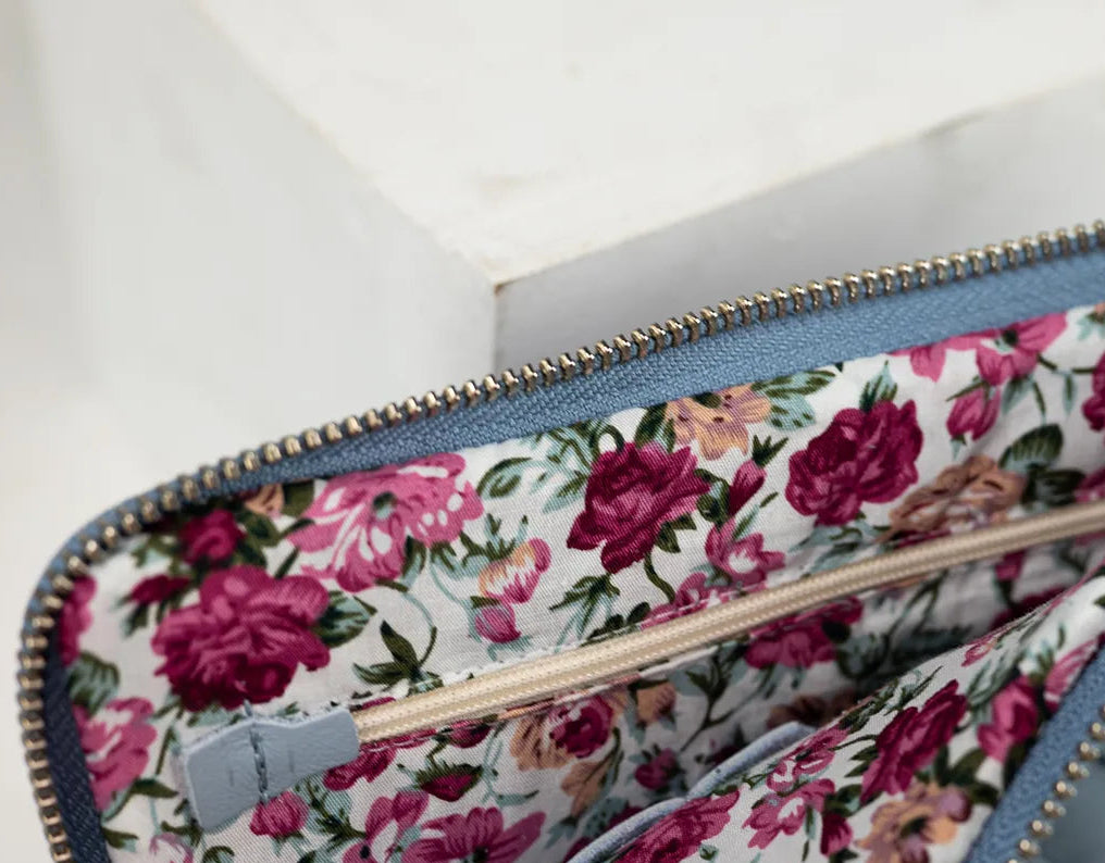 Floral-patterned clutch with a textured blue interior on a white background