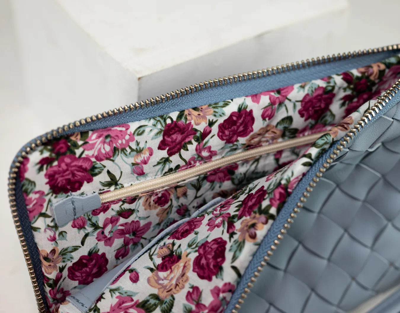 Floral-patterned clutch with a textured blue interior on a white background
