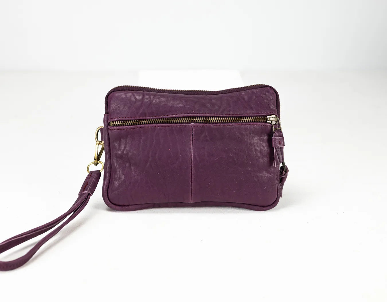 Purple leather clutch bag with a strap on a white background