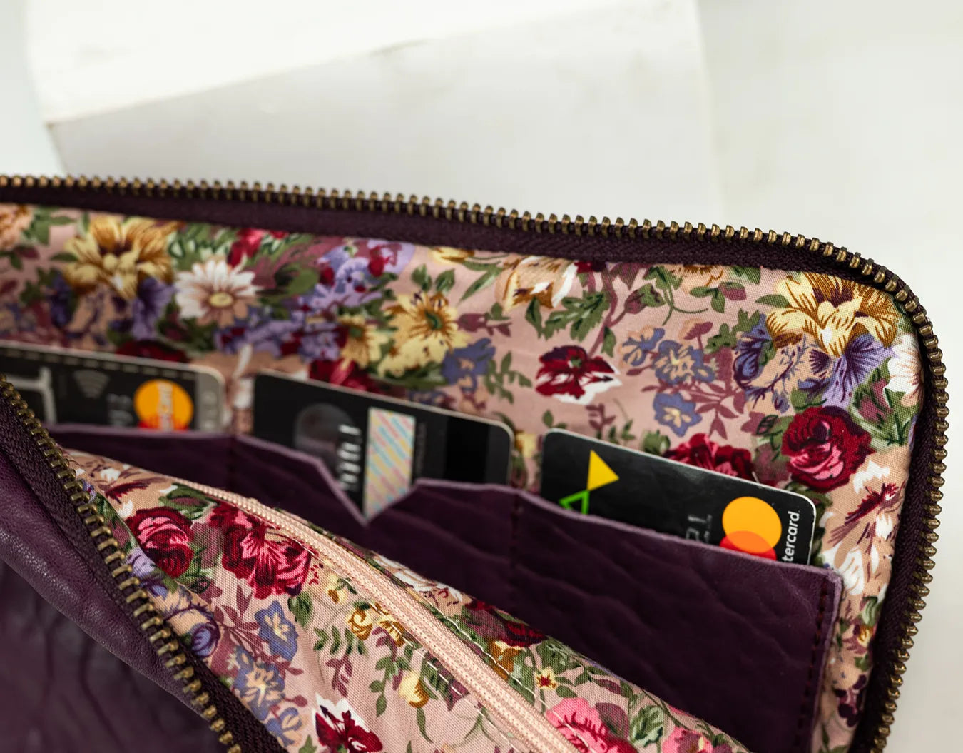 Purple leather bag with a gold zipper on a white background
