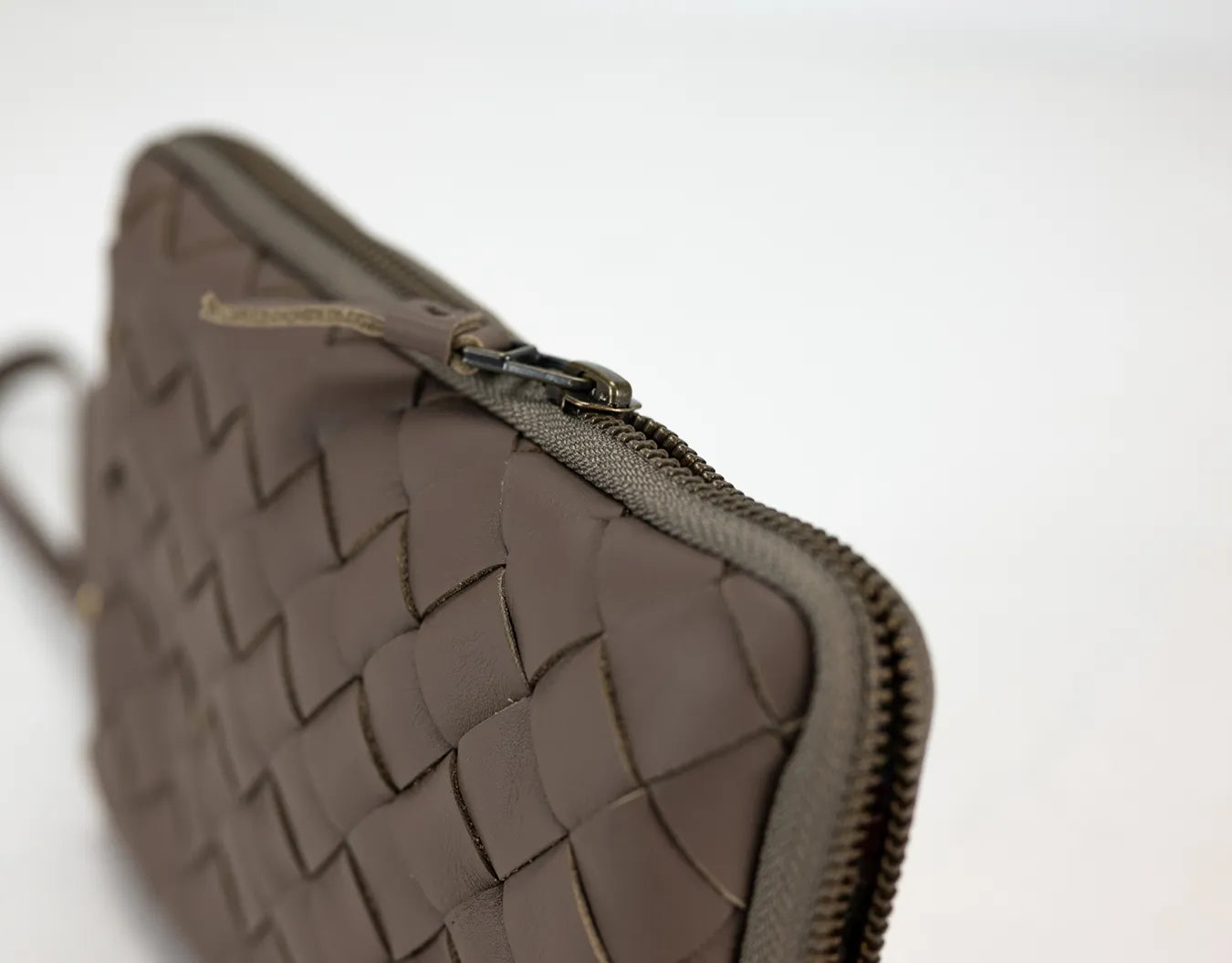 Brown woven clutch bag with a zipper on a white background
