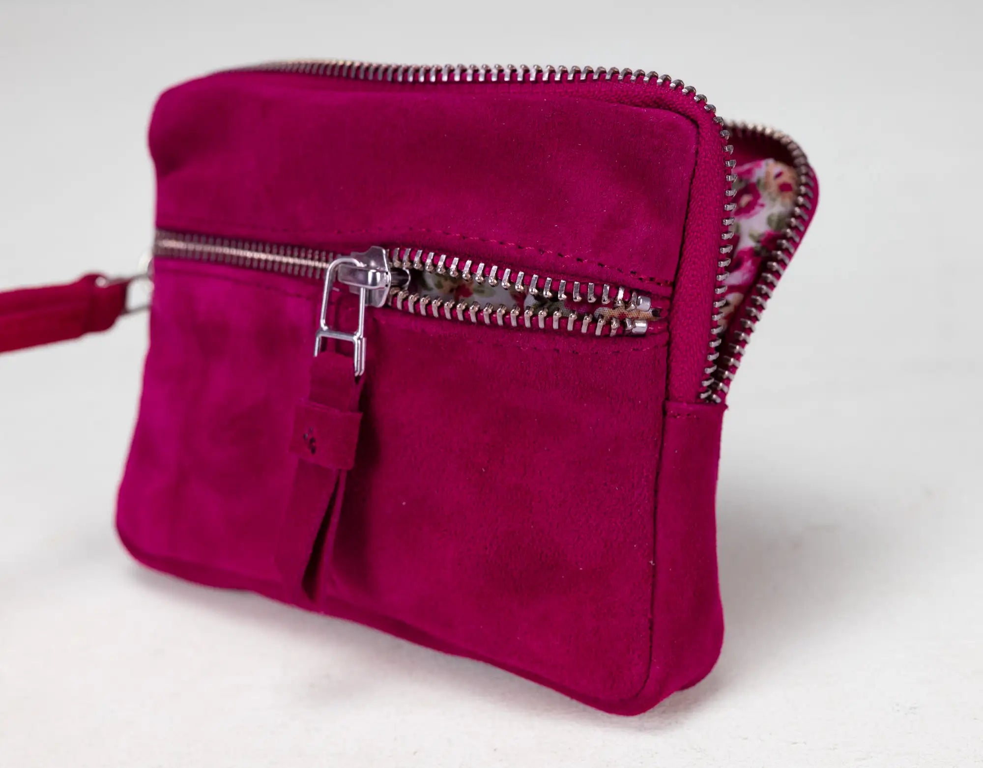 Pink suede handbag with a zipper on a light gray background