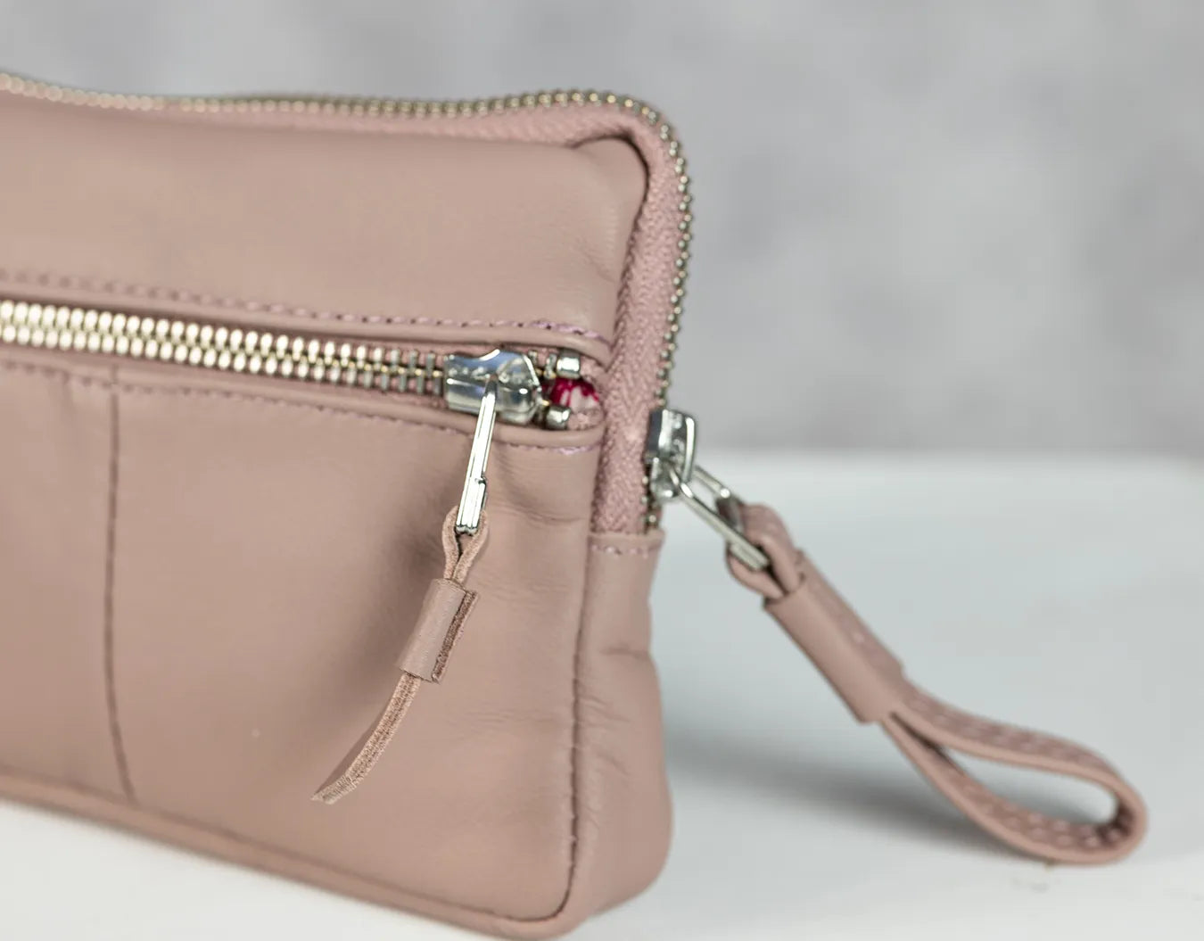 Pink wristlet with a zipper on a light gray background