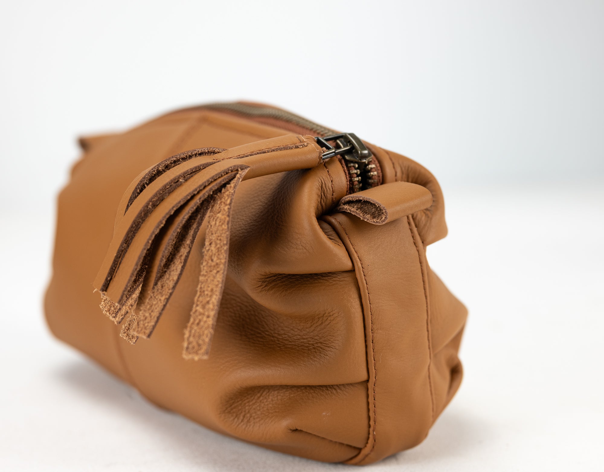 Brown leather bag with a tassel on a white background
