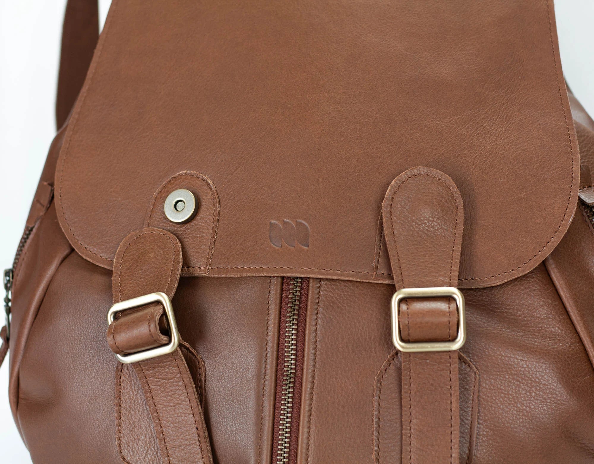 Brown leather backpack with gold buckles on a white background
