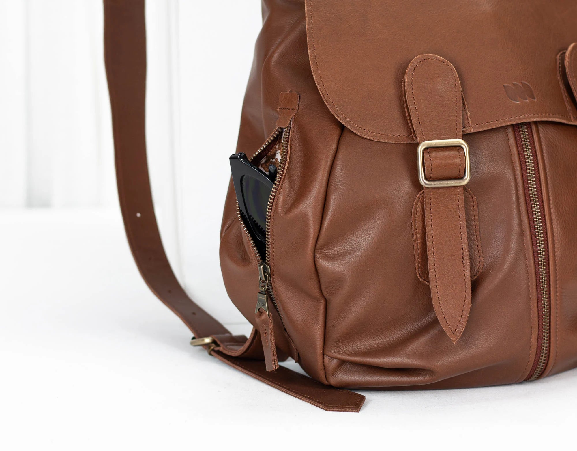 Brown leather backpack with gold buckle on a white background