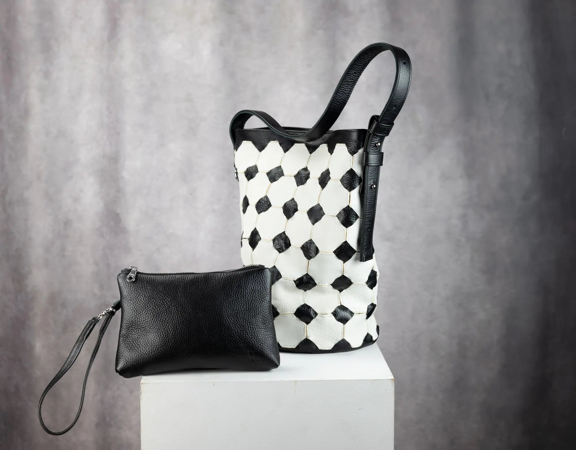 Black and white woven handbag with a matching clutch on a gray background