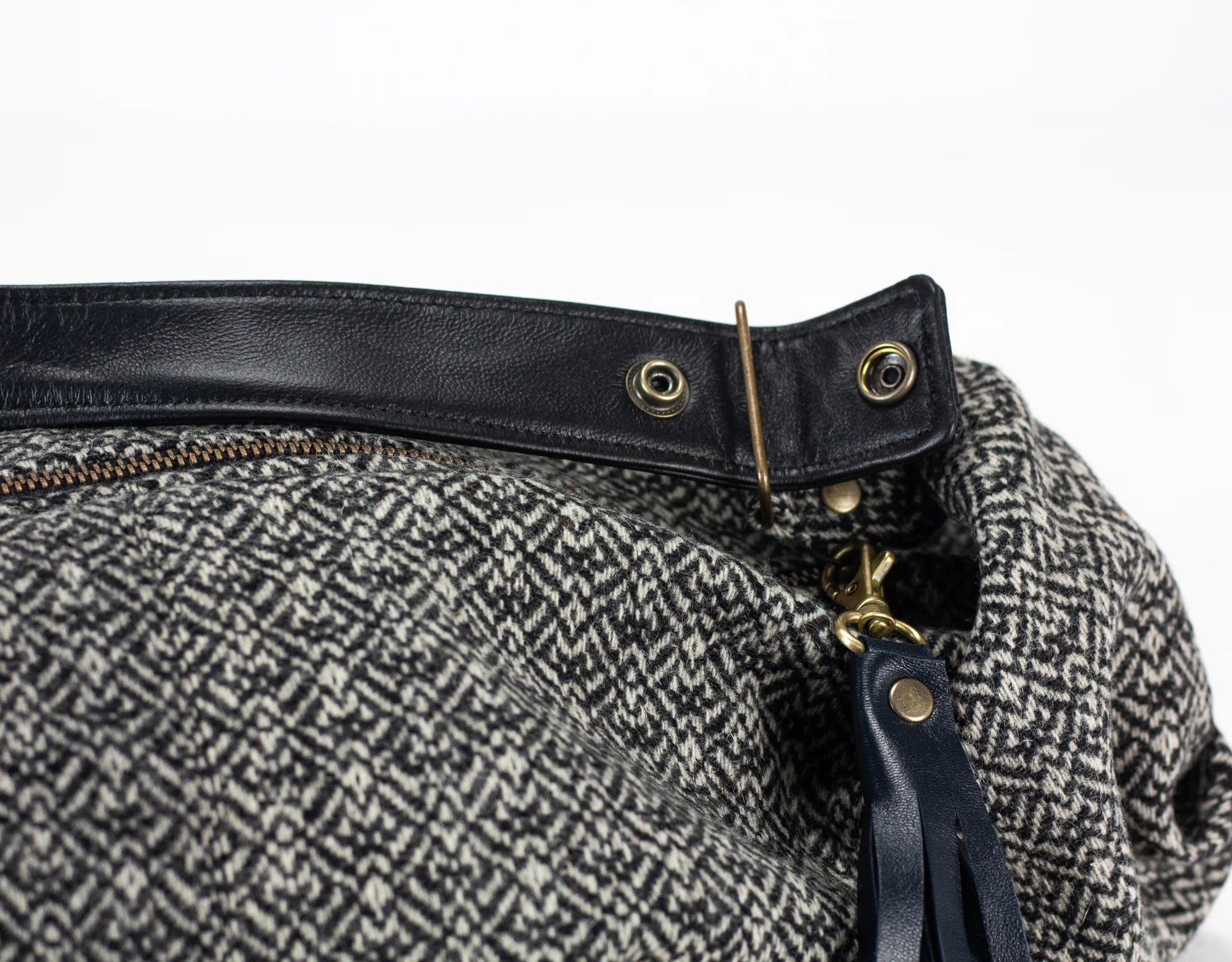 Close-up of a bag with black leather strap and gold hardware on a white background