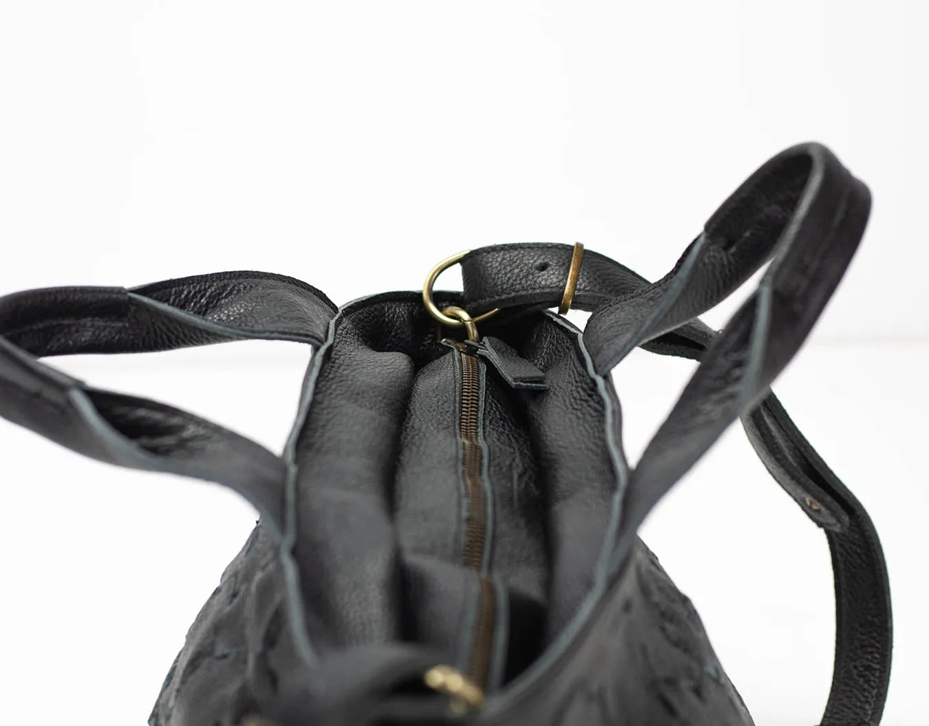 Black leather backpack with a gold zipper on a white background
