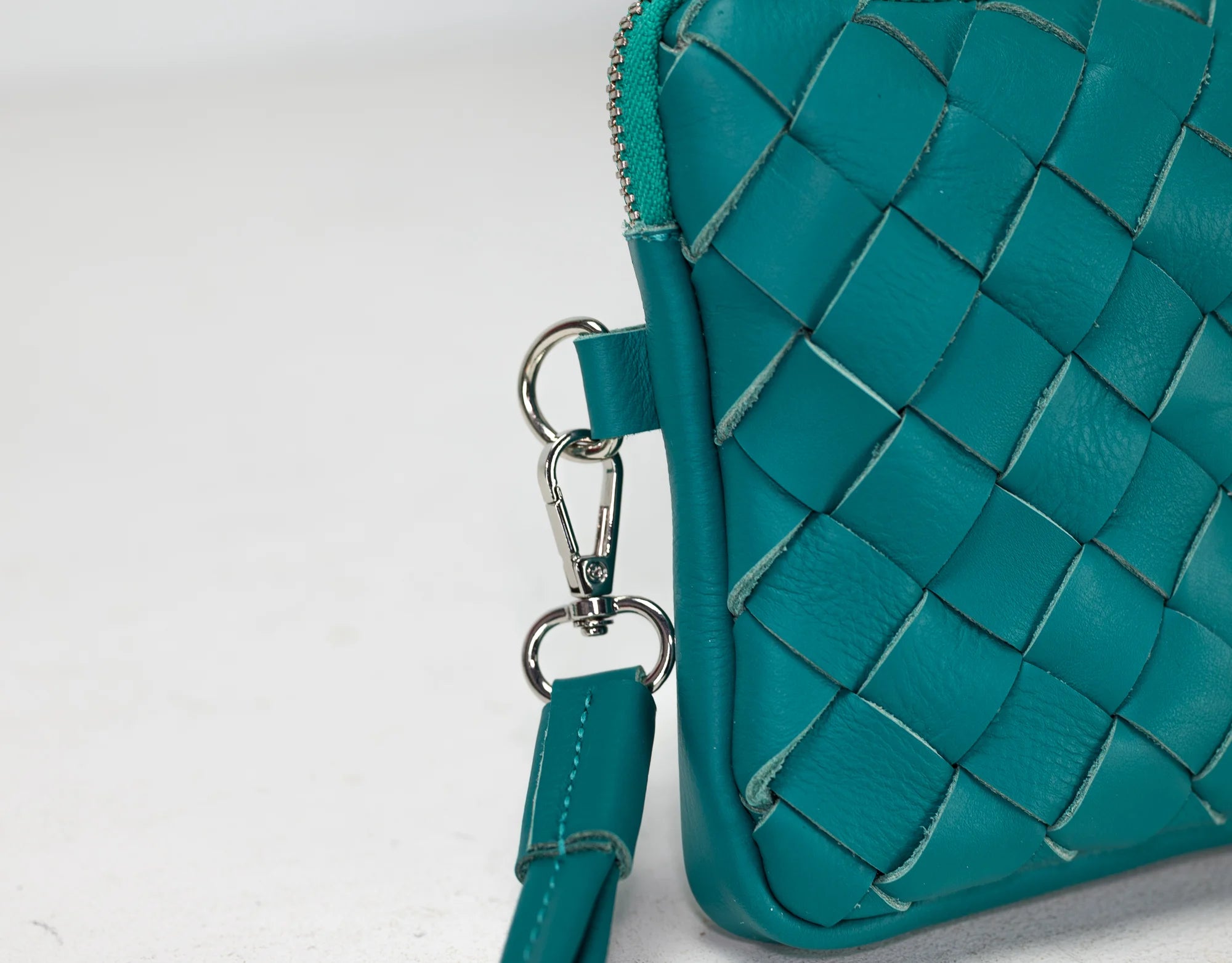 Teal woven handbag with a strap on a white background