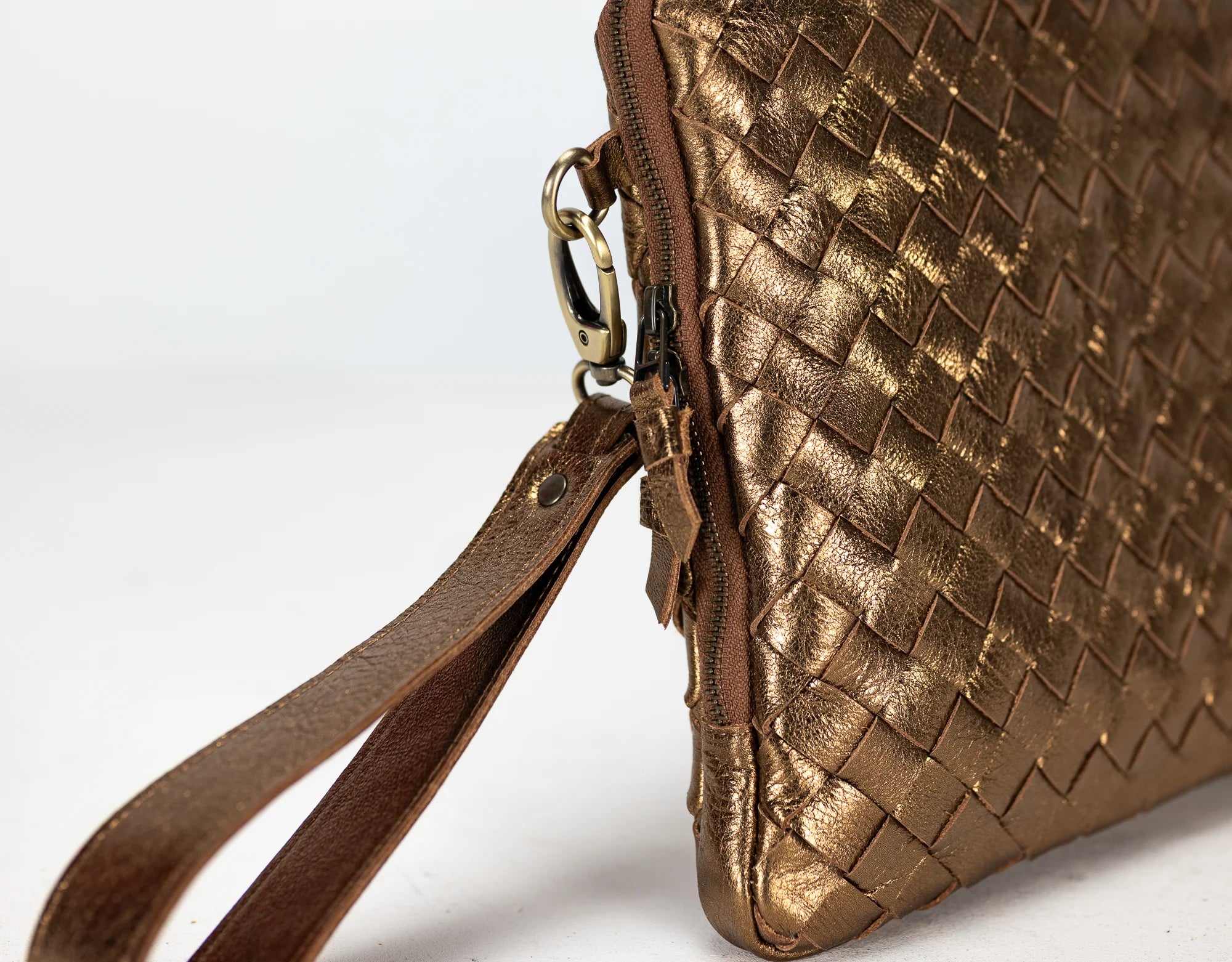 Gold woven handbag with a strap on a white background