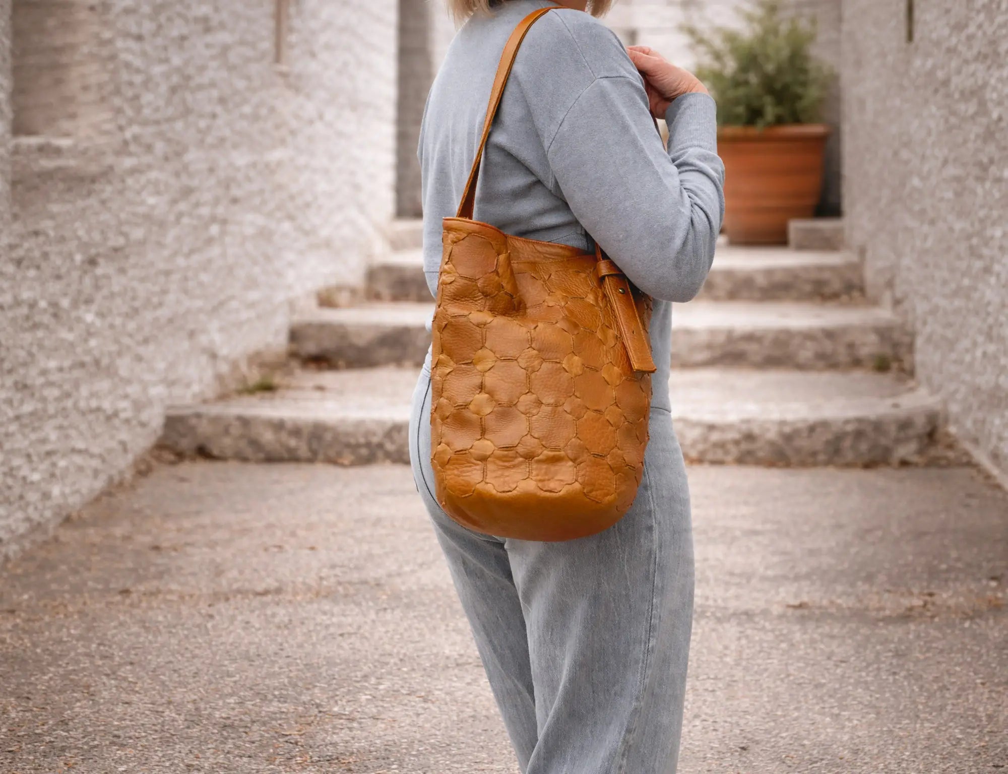 Person wearing a textured mustard yellow bag outdoors on stone steps.