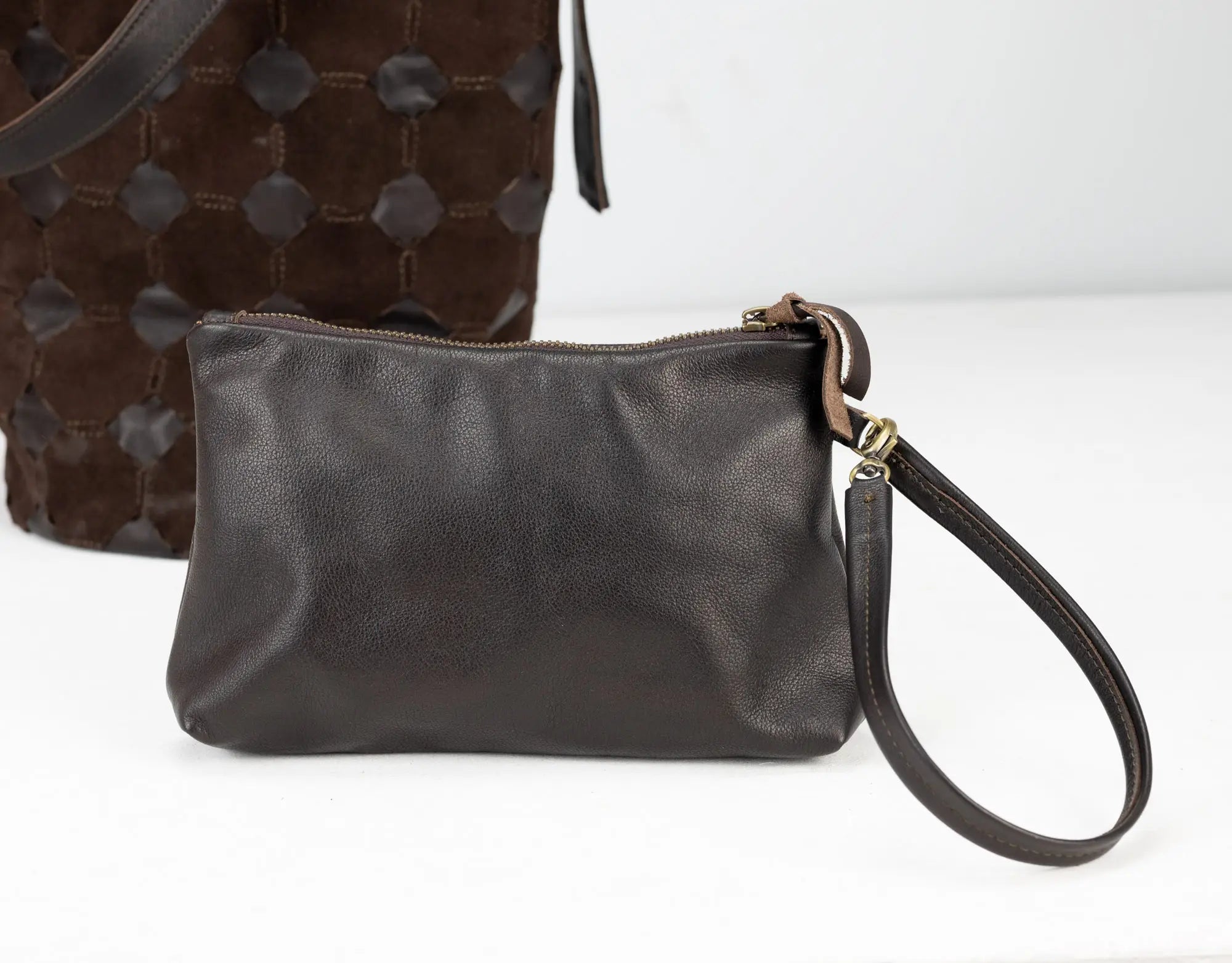 Brown leather clutch bag with a strap on a white background