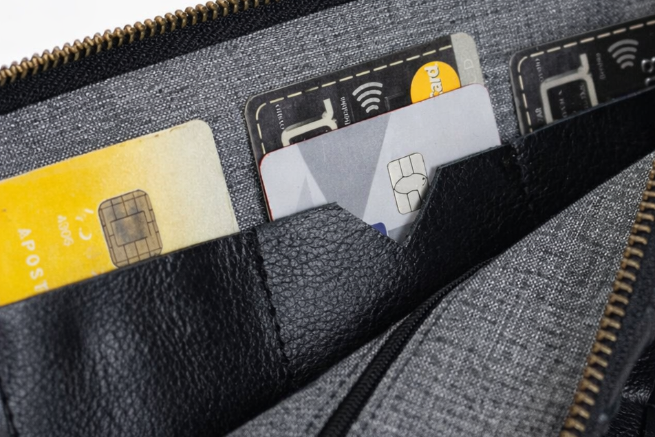 Black woven leather handbag with a zipper open, revealing credit cards inside.