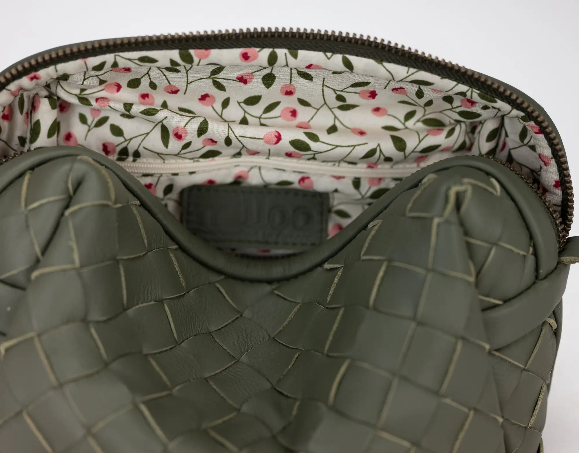 Green textured bag with floral lining on a white background