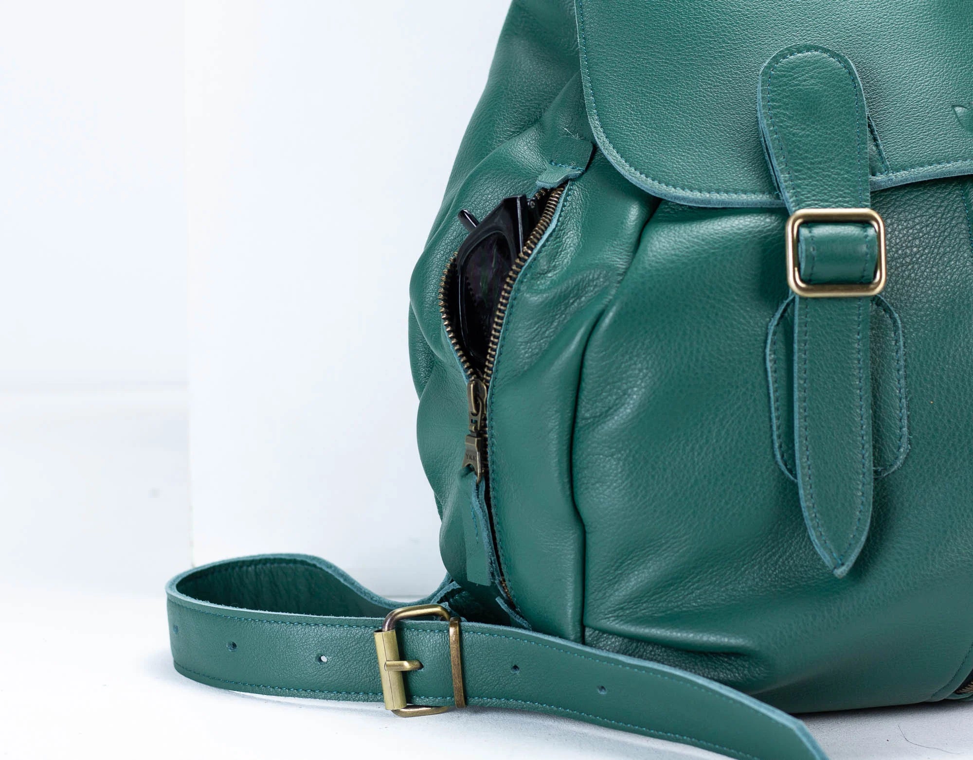 Green leather backpack with gold buckles on a white background