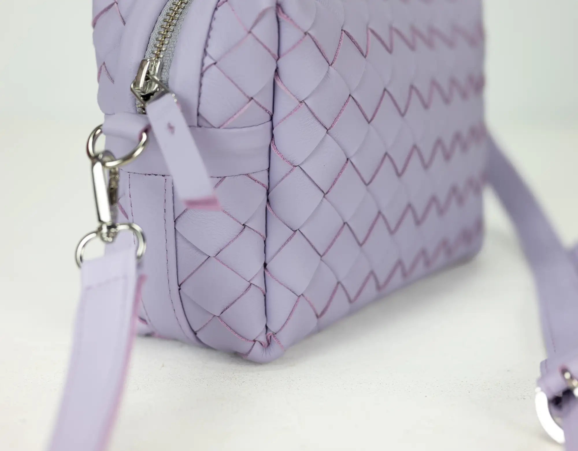 Purple quilted handbag with a strap on a white background
