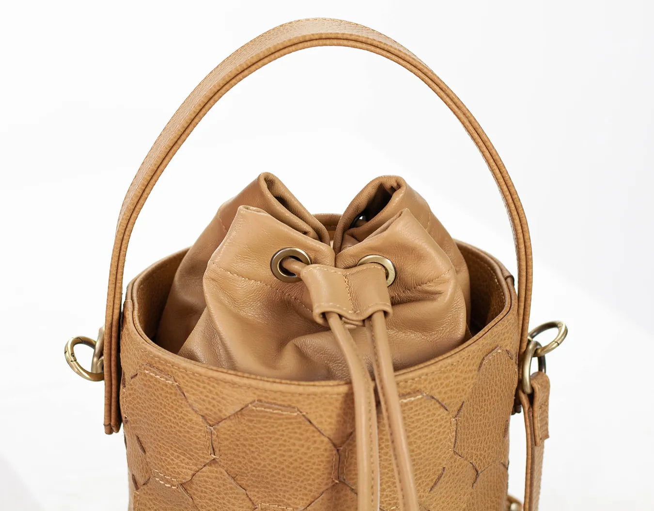 Tan quilted bucket bag with drawstring on a white background