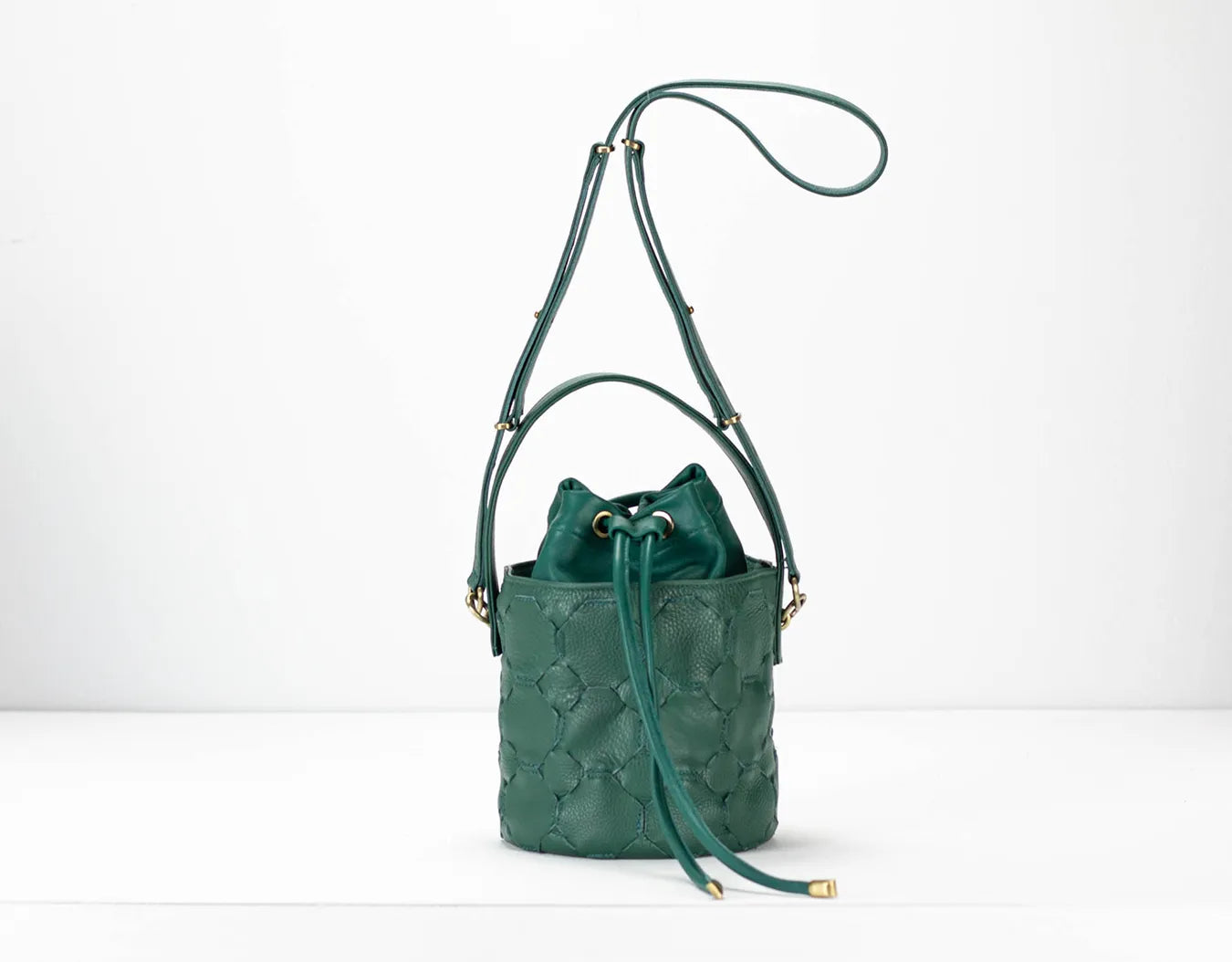 Green leather bucket bag with drawstring on a white background