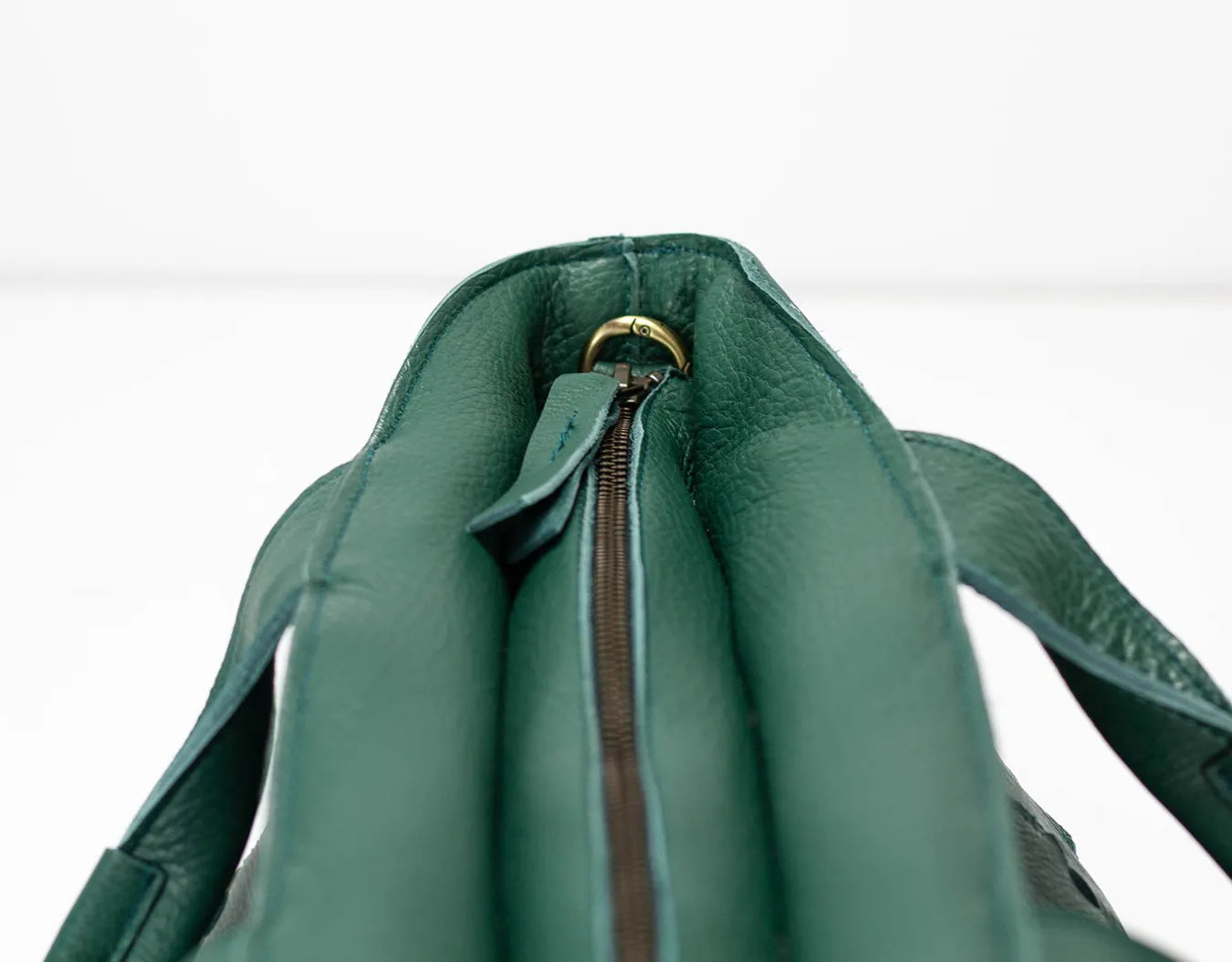 Green leather bag with a zipper on a white background