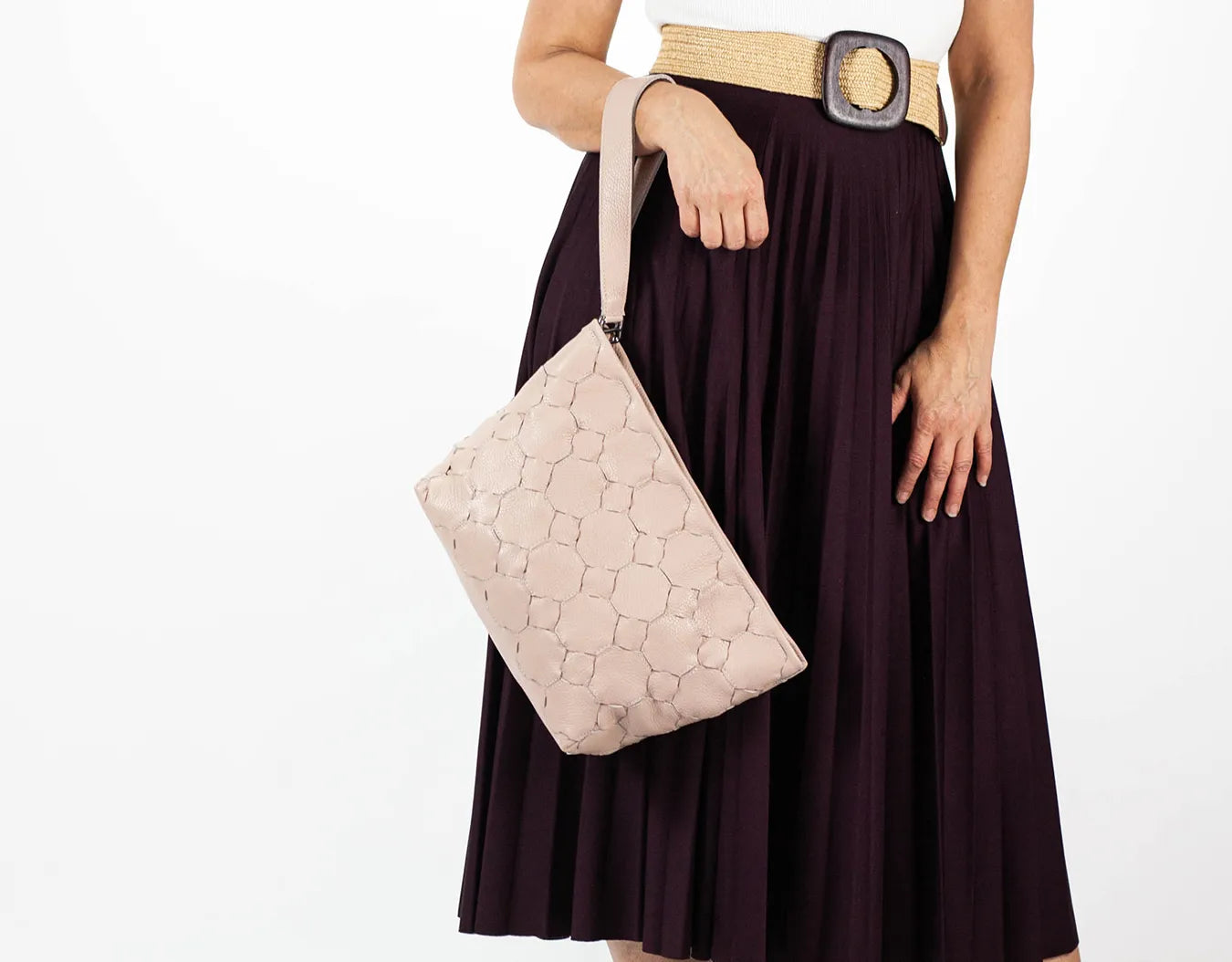 Person holding a light pink handbag with a plain background