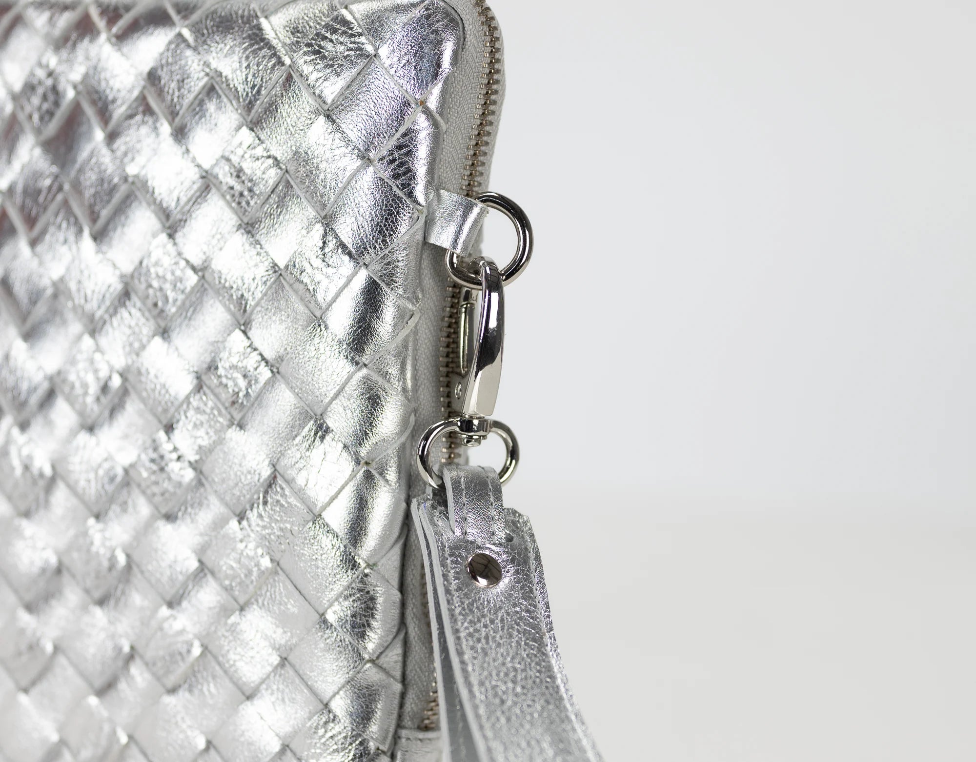 Silver woven clutch bag with a zipper on a white background