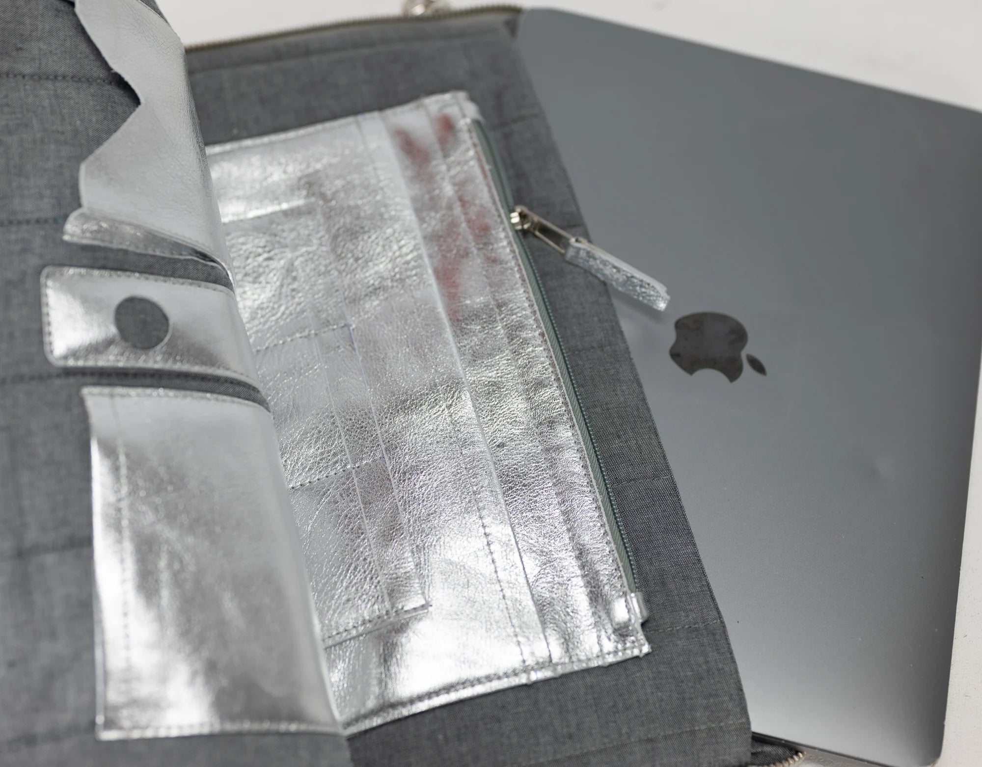 Gray laptop case with a silver laptop inside, showing Apple logo.