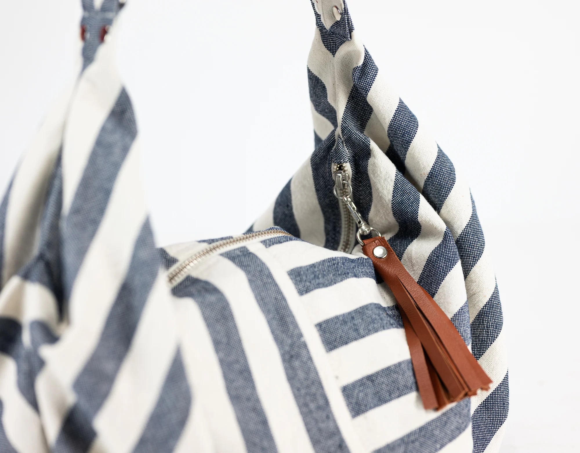 Blue and white striped bag with a brown tassel on a white background