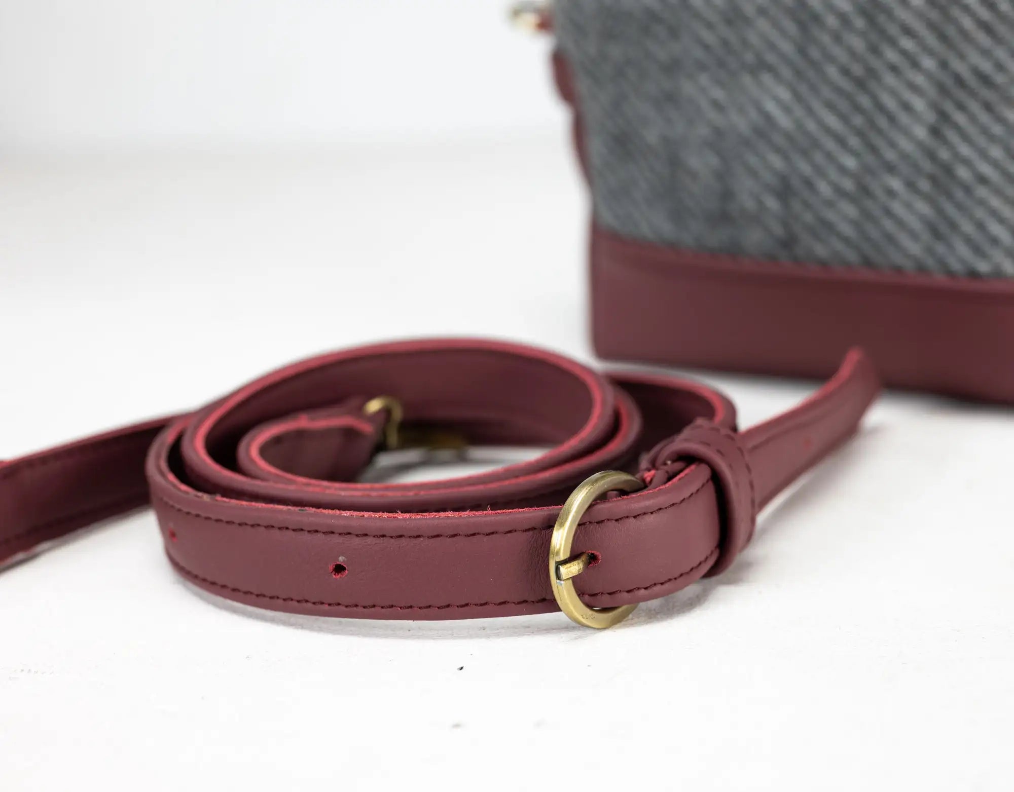 Maroon leather strap with gold buckle on a white background