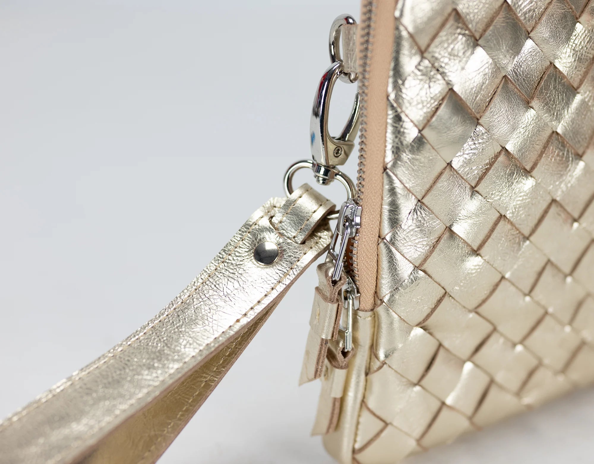 Gold woven handbag with a strap on a light gray background