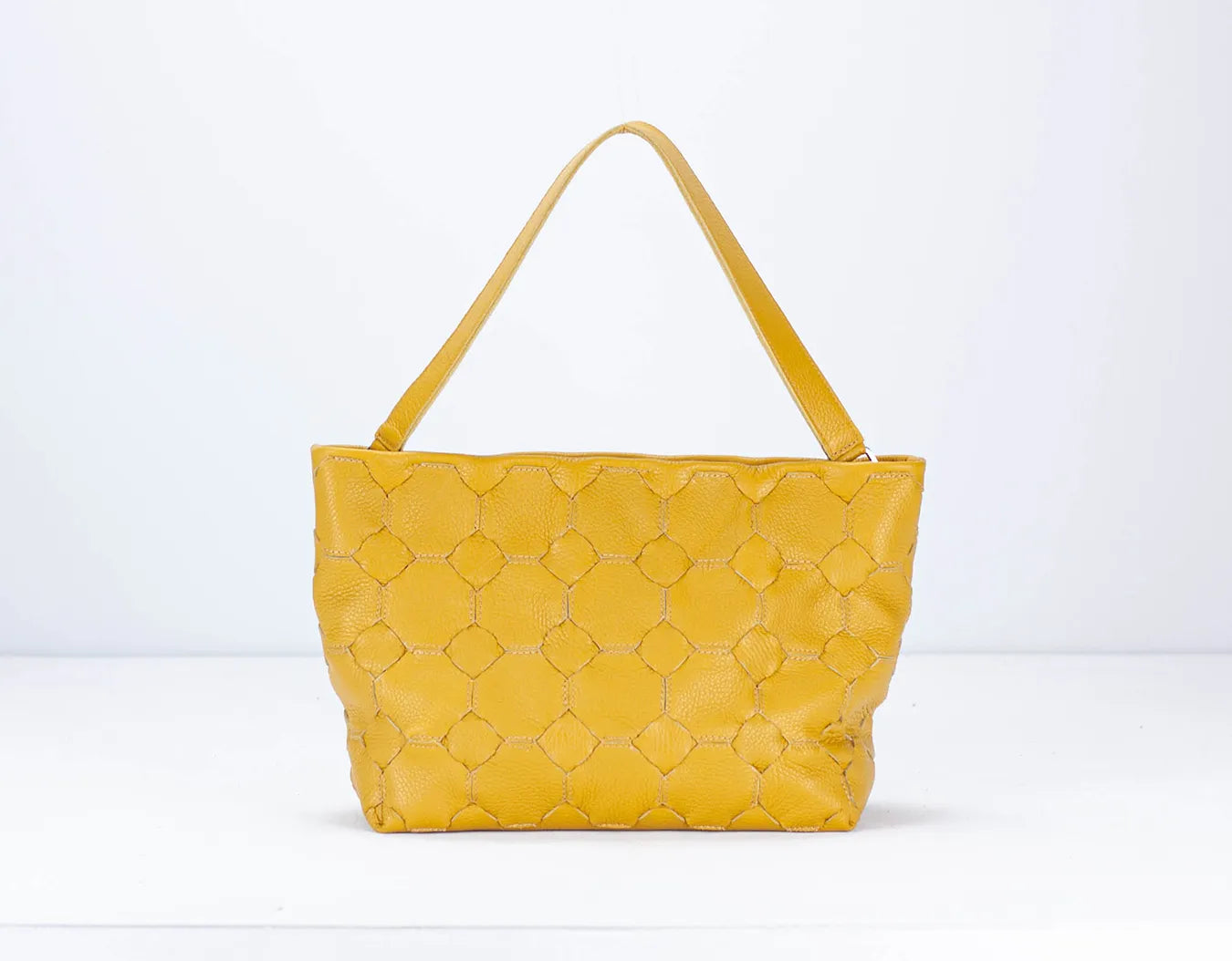 Yellow quilted handbag on a white background