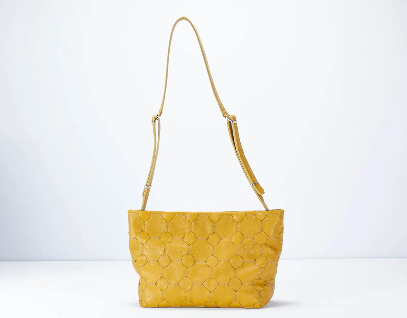 Yellow quilted handbag with a strap on a white background