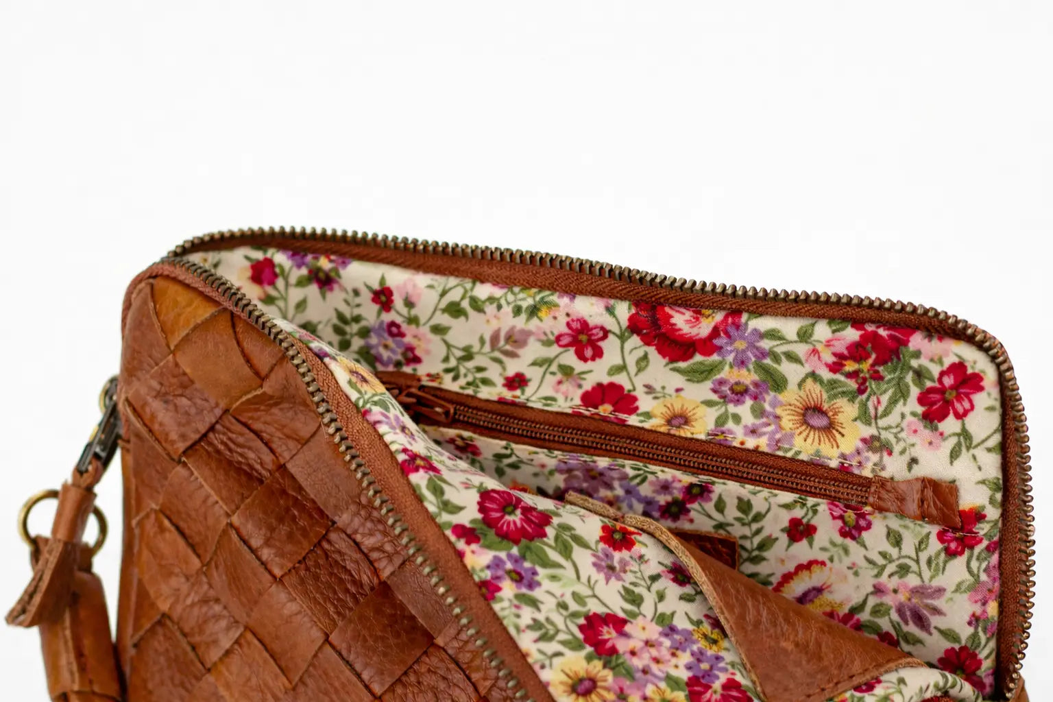 Brown leather clutch with floral lining on a white background
