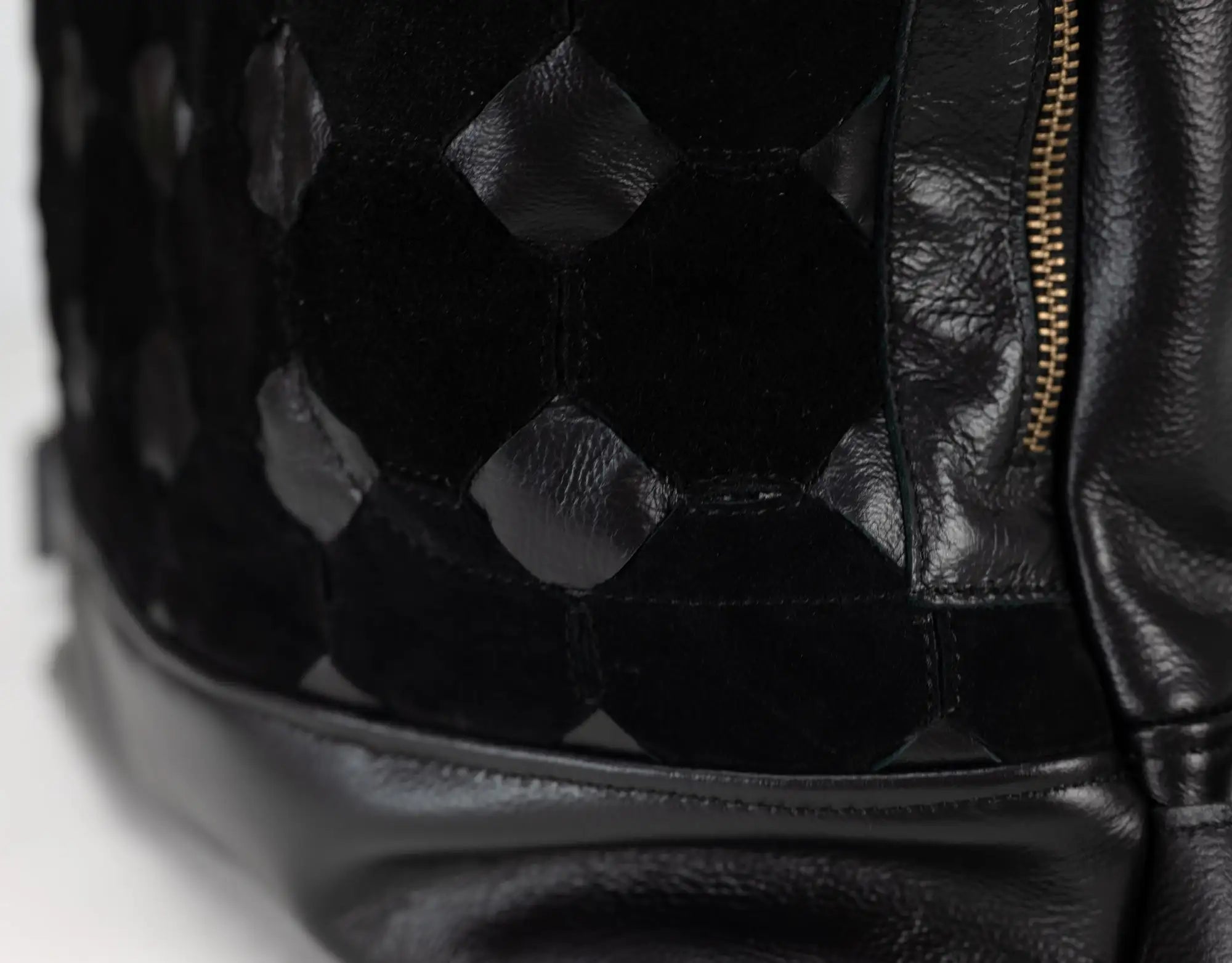 Close-up of a black leather handbag with geometric pattern