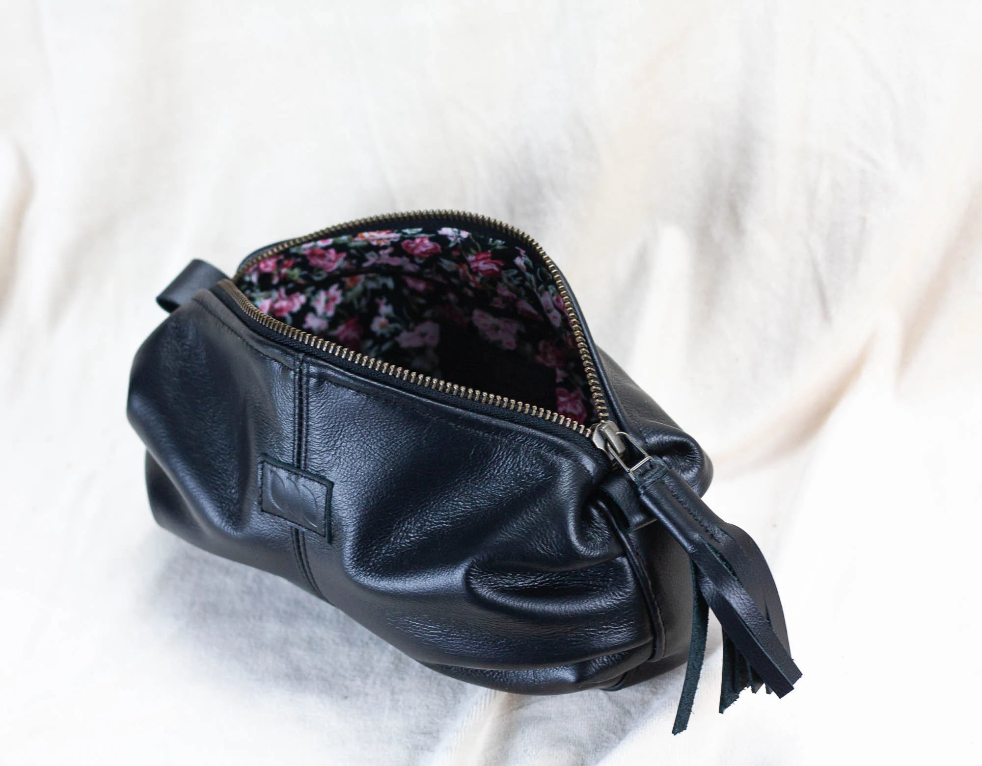 Black leather clutch with floral interior on a white background