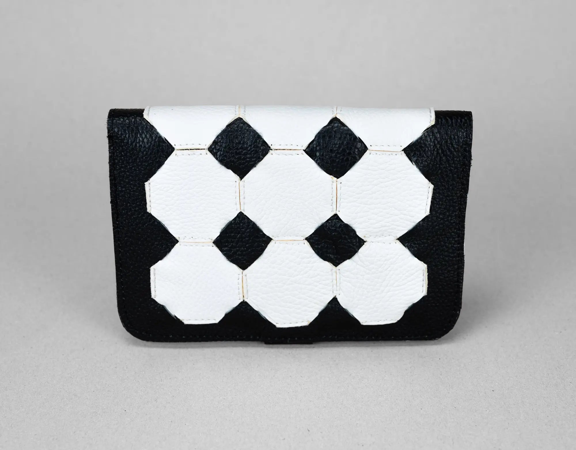 Black and white geometric patterned clutch bag on a gray background