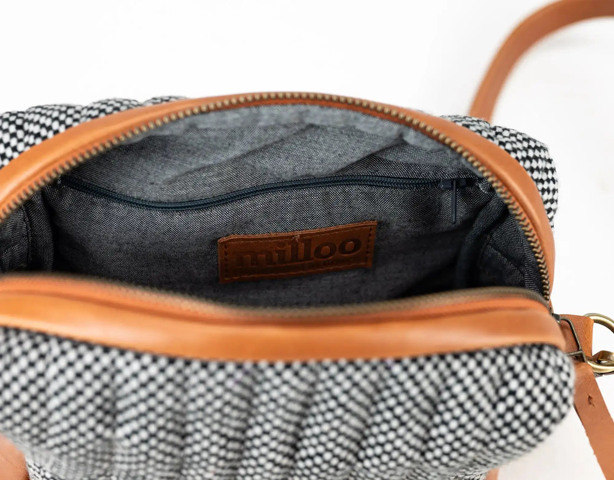 Open handbag with checkered pattern and brown leather trim, featuring a brand logo.