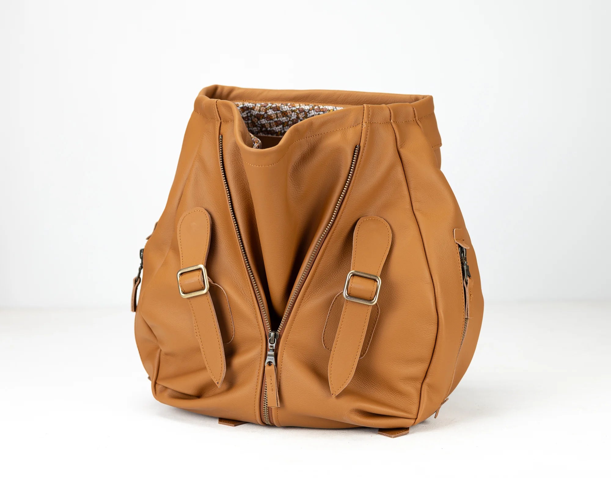 Brown leather bag with zippers and straps on a white background