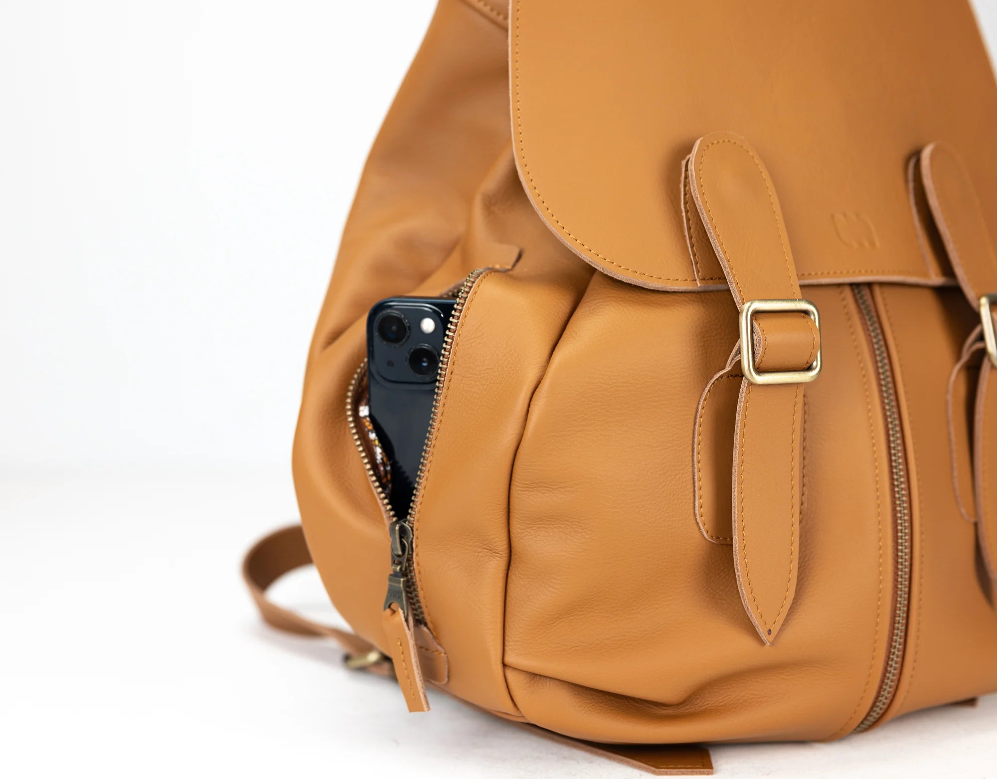 Brown leather backpack with a phone in a pocket on a white background