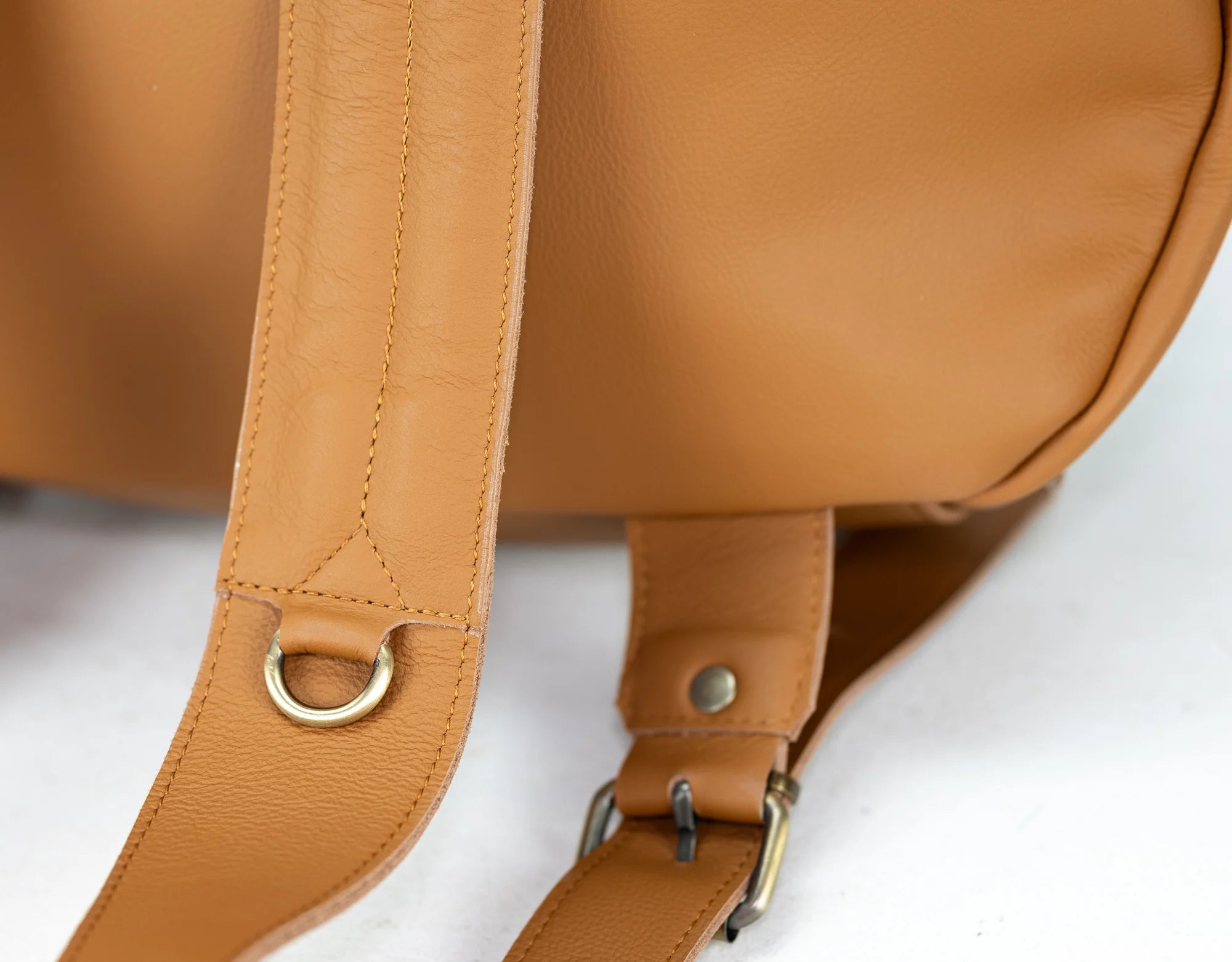 Close-up of a brown leather bag with strap and buckle on a white background