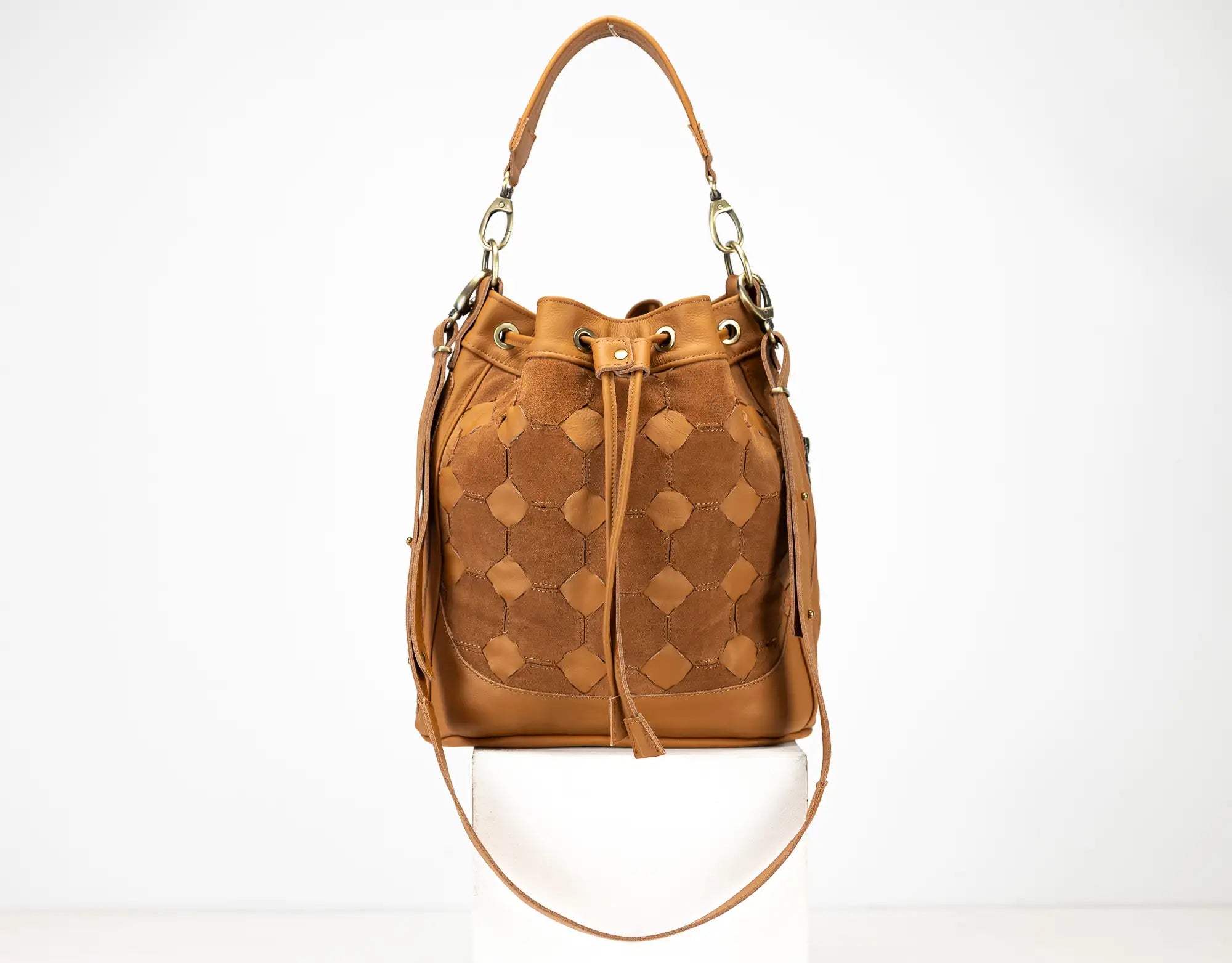 Brown leather bucket bag with geometric pattern on a white background