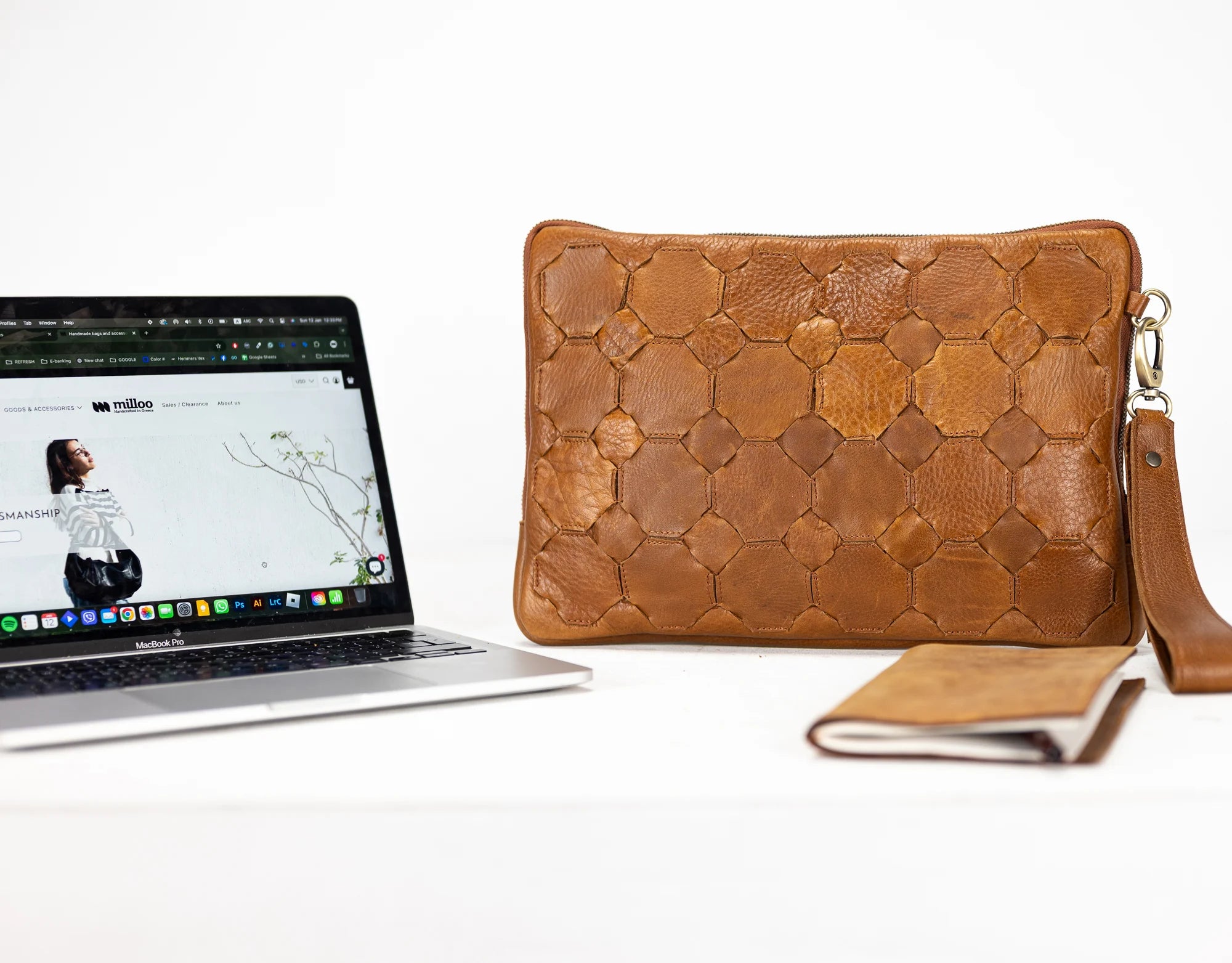 Brown woven leather clutch next to a laptop on a white background