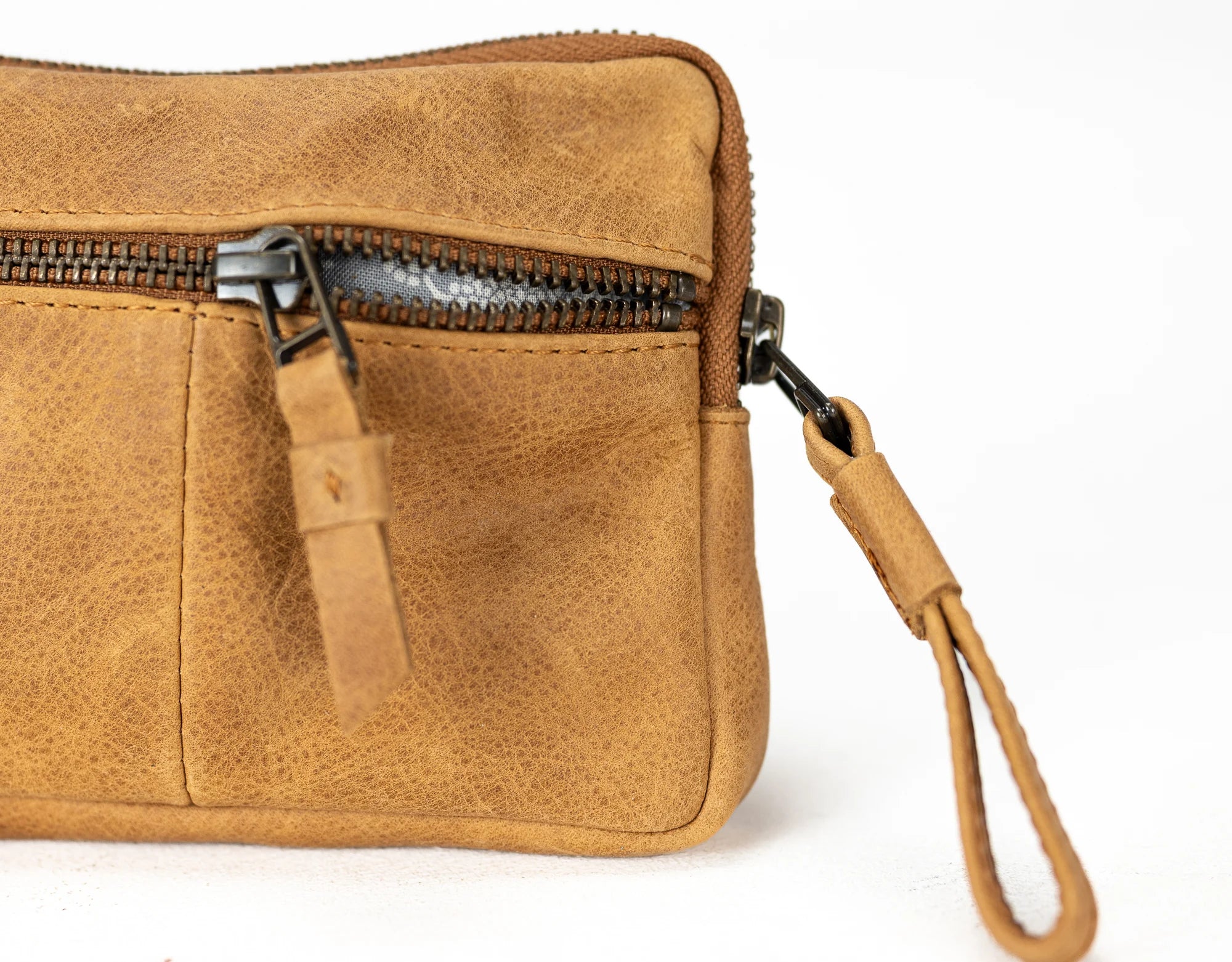 Brown leather clutch bag with a strap on a white background