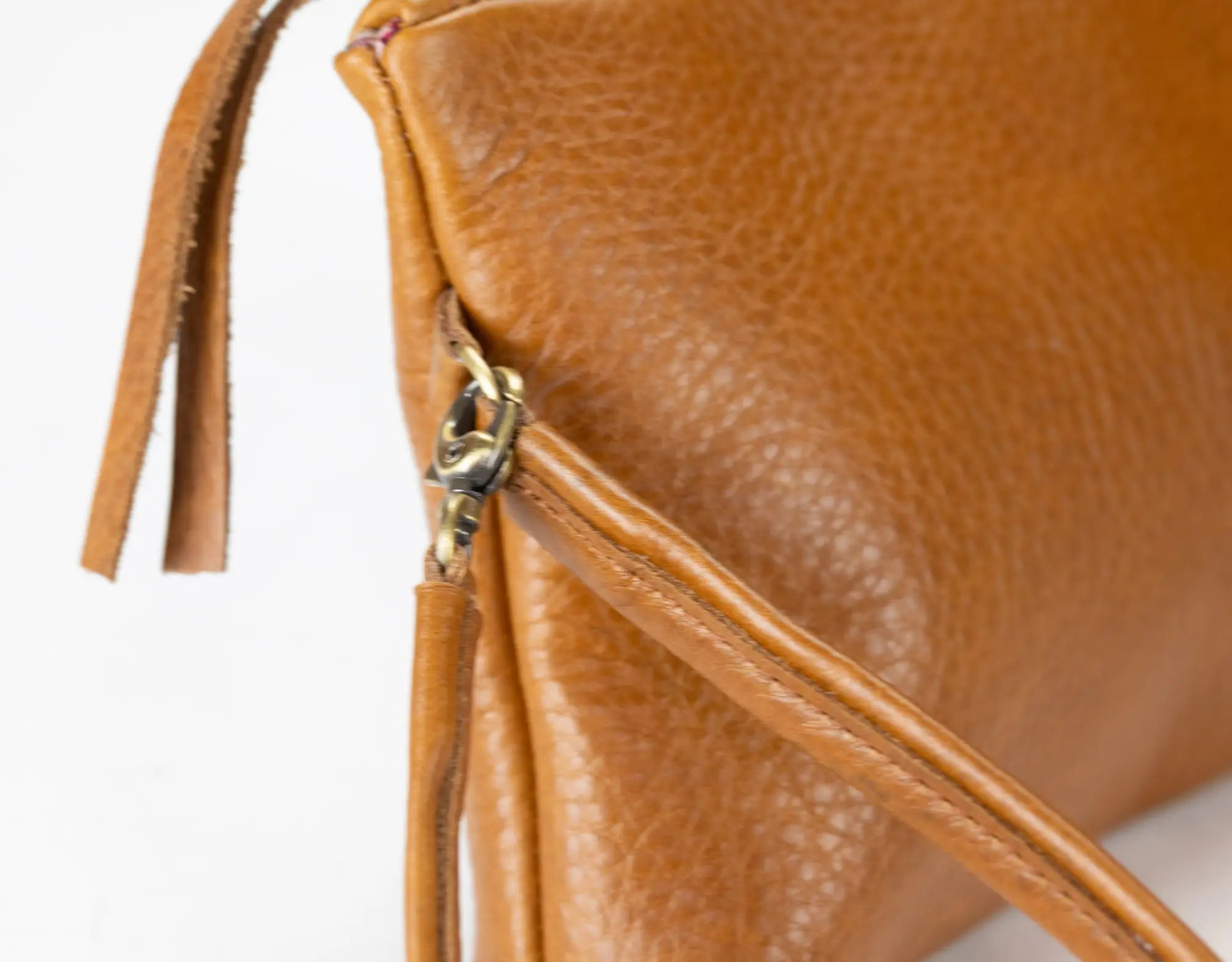 Close-up of a brown leather handbag with a strap on a light background