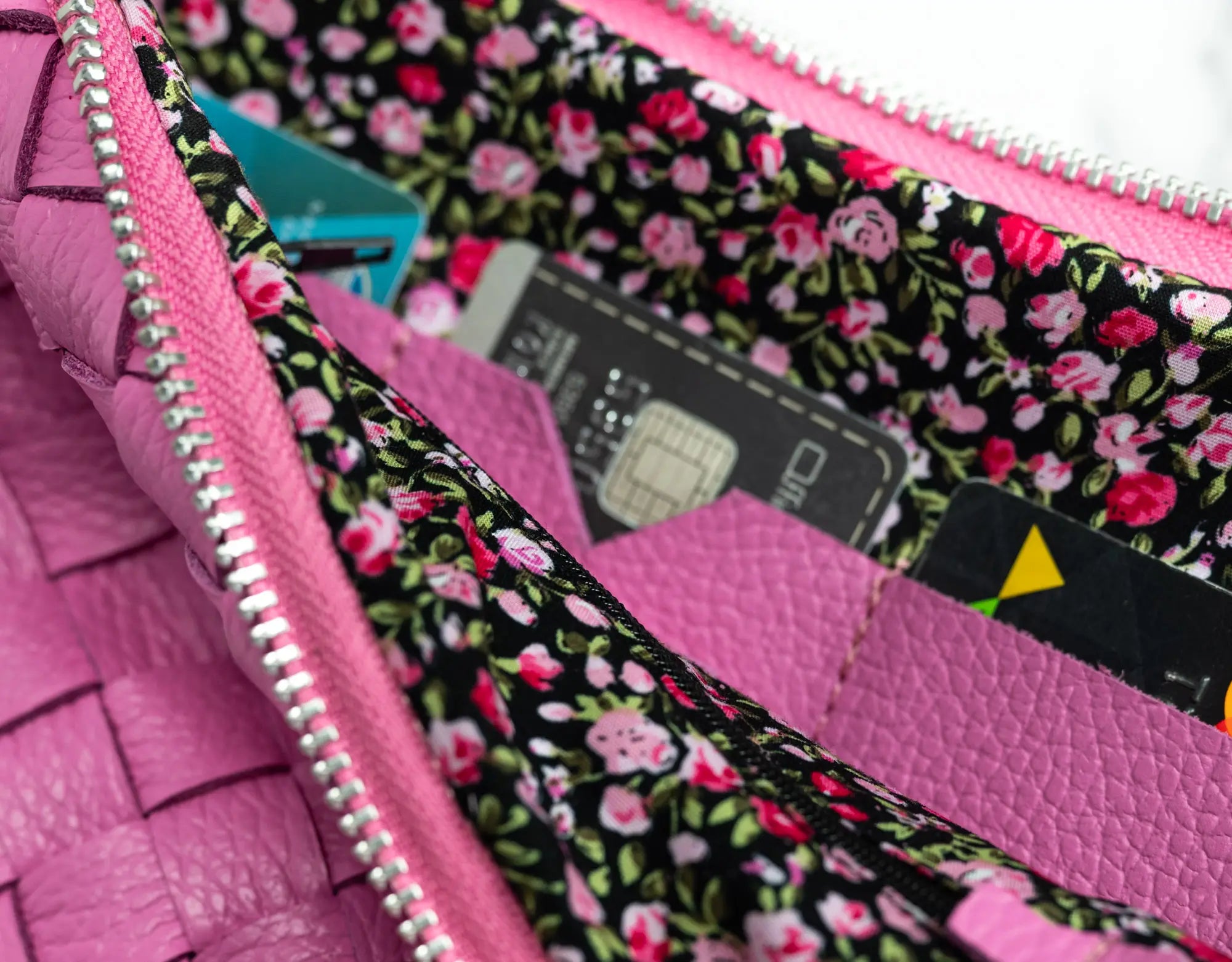 Close-up of a pink wallet with floral lining, showing cards and a pen.