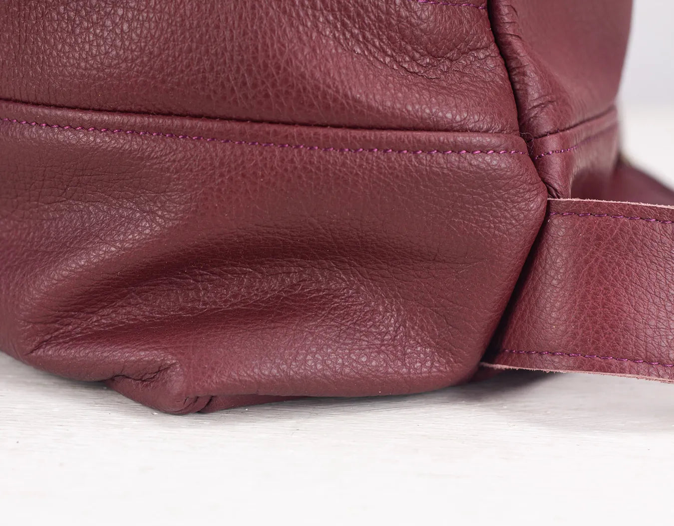 Close-up of a maroon leather bag on a light background