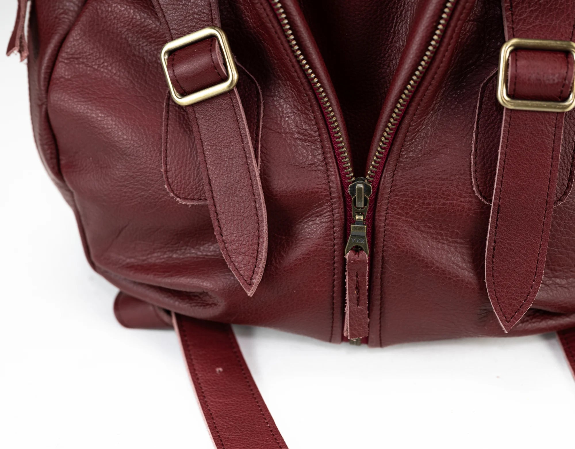 Maroon leather bag with gold buckles on a white background