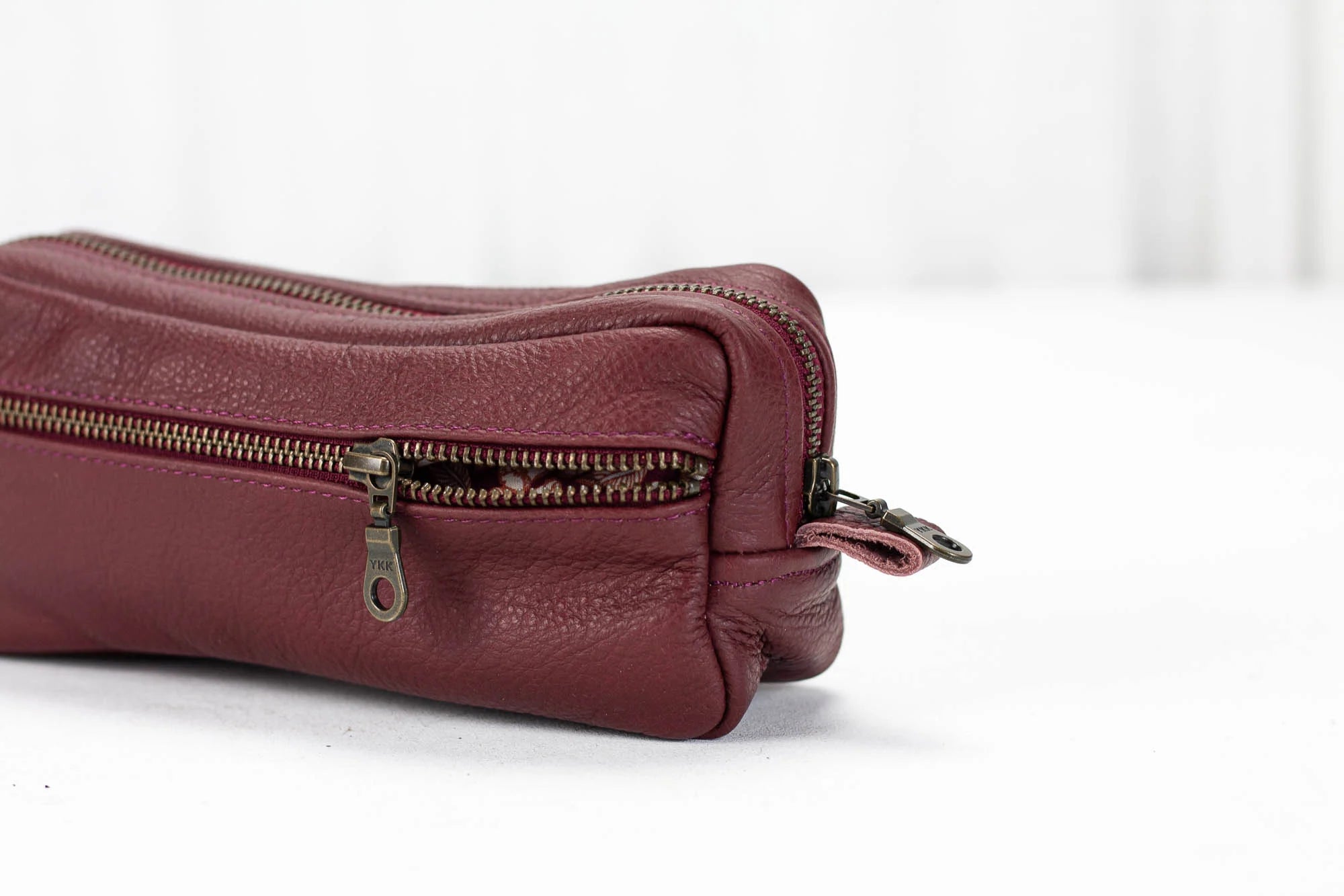 Maroon leather pouch with a zipper on a white background