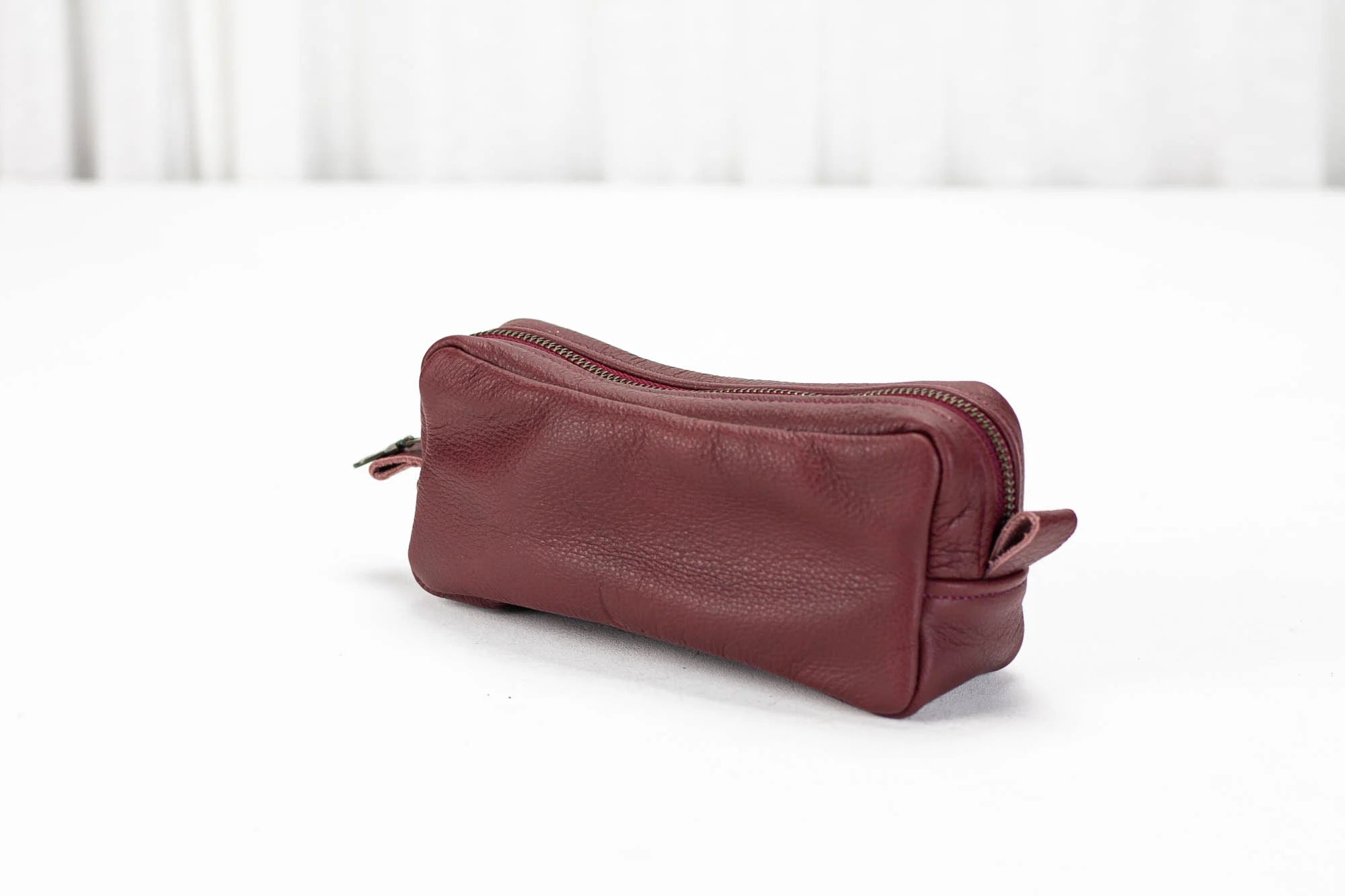 Maroon leather toiletry bag on a white background
