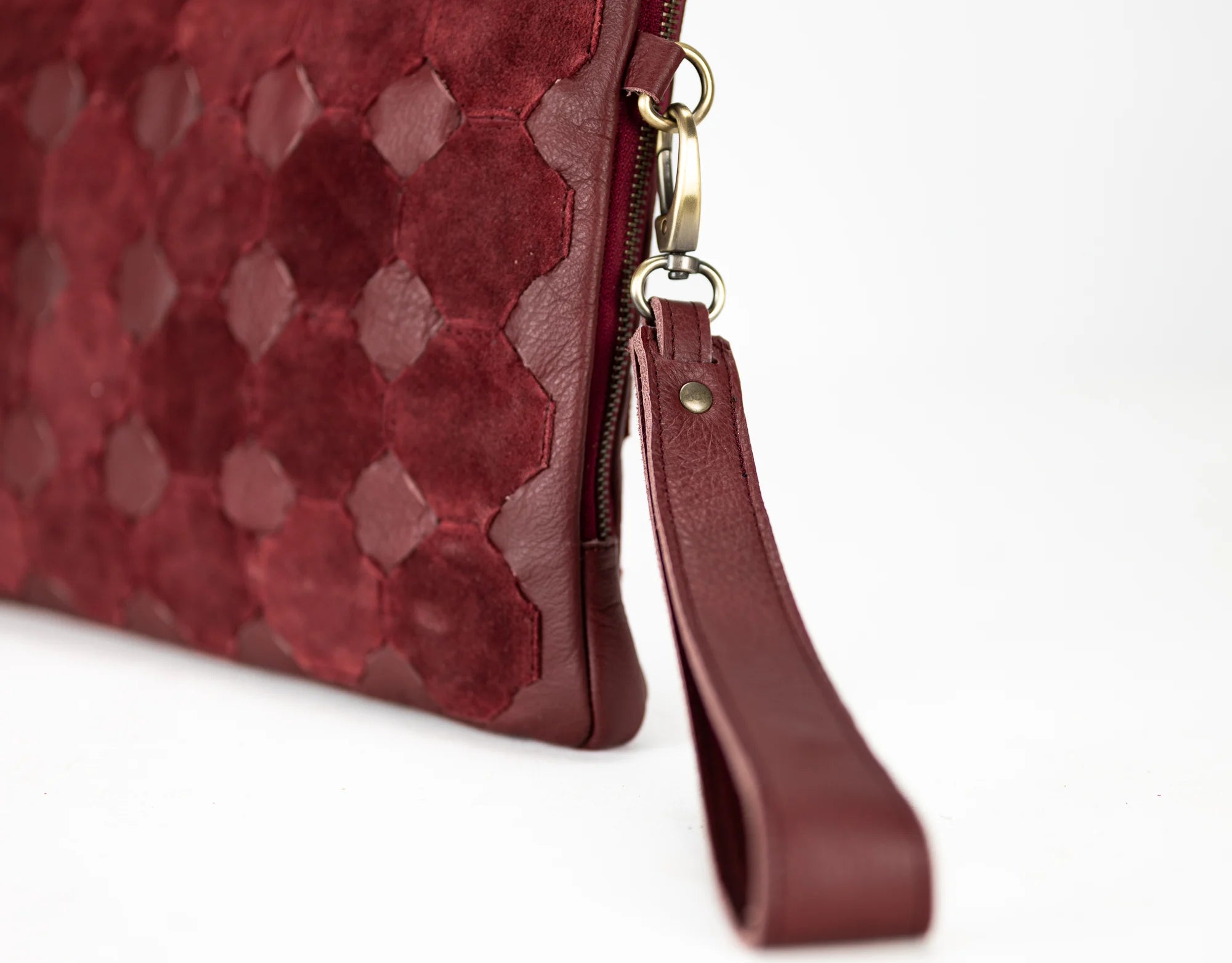 Close-up of a red textured clutch bag with a strap on a white background